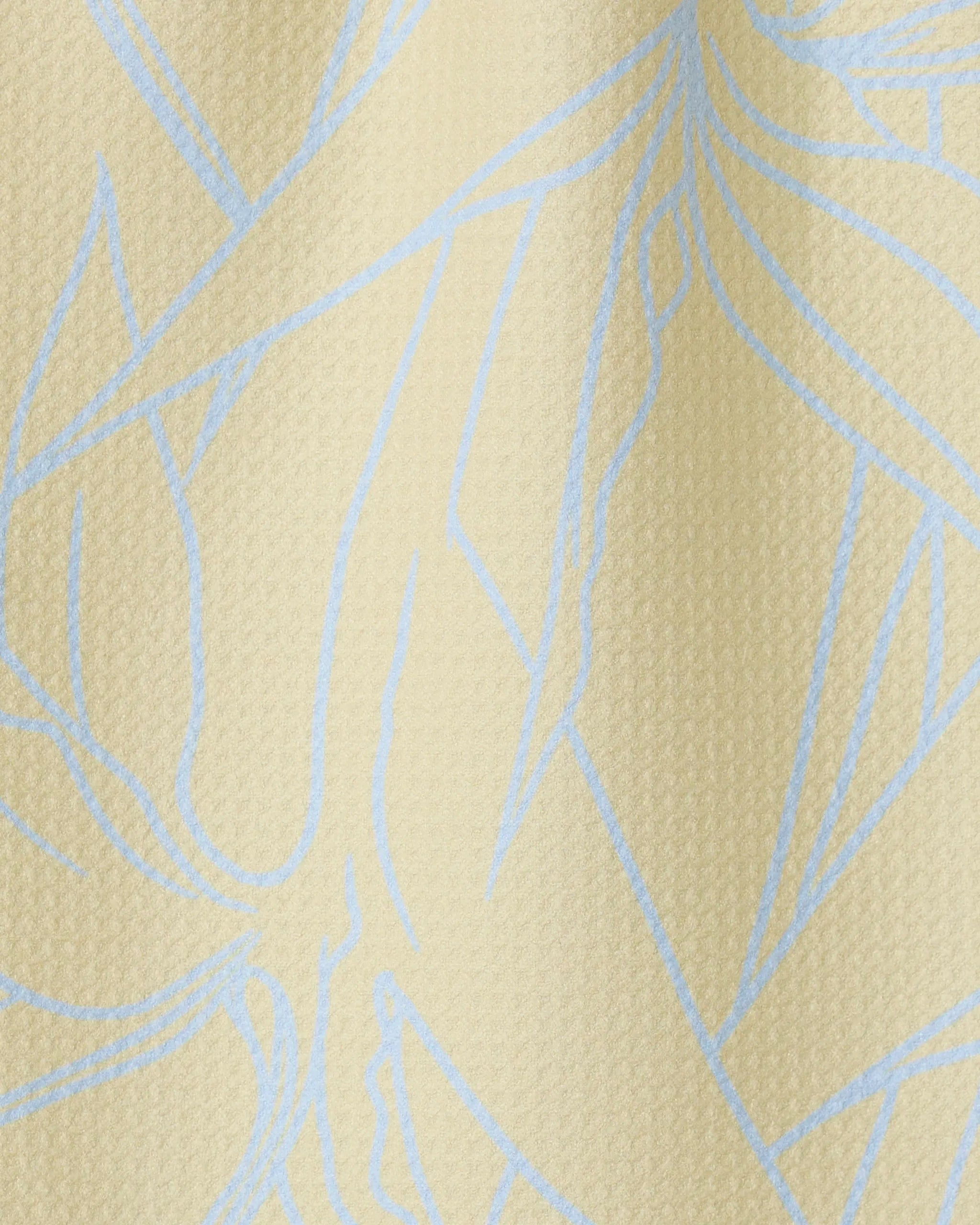 Close-up of Paradise Blooms by GEOMETRY—a textured, light beige towel featuring abstract blue lines. The ultra-absorbent, wavy surface with subtle shadows highlights its soft, high-quality fabric.