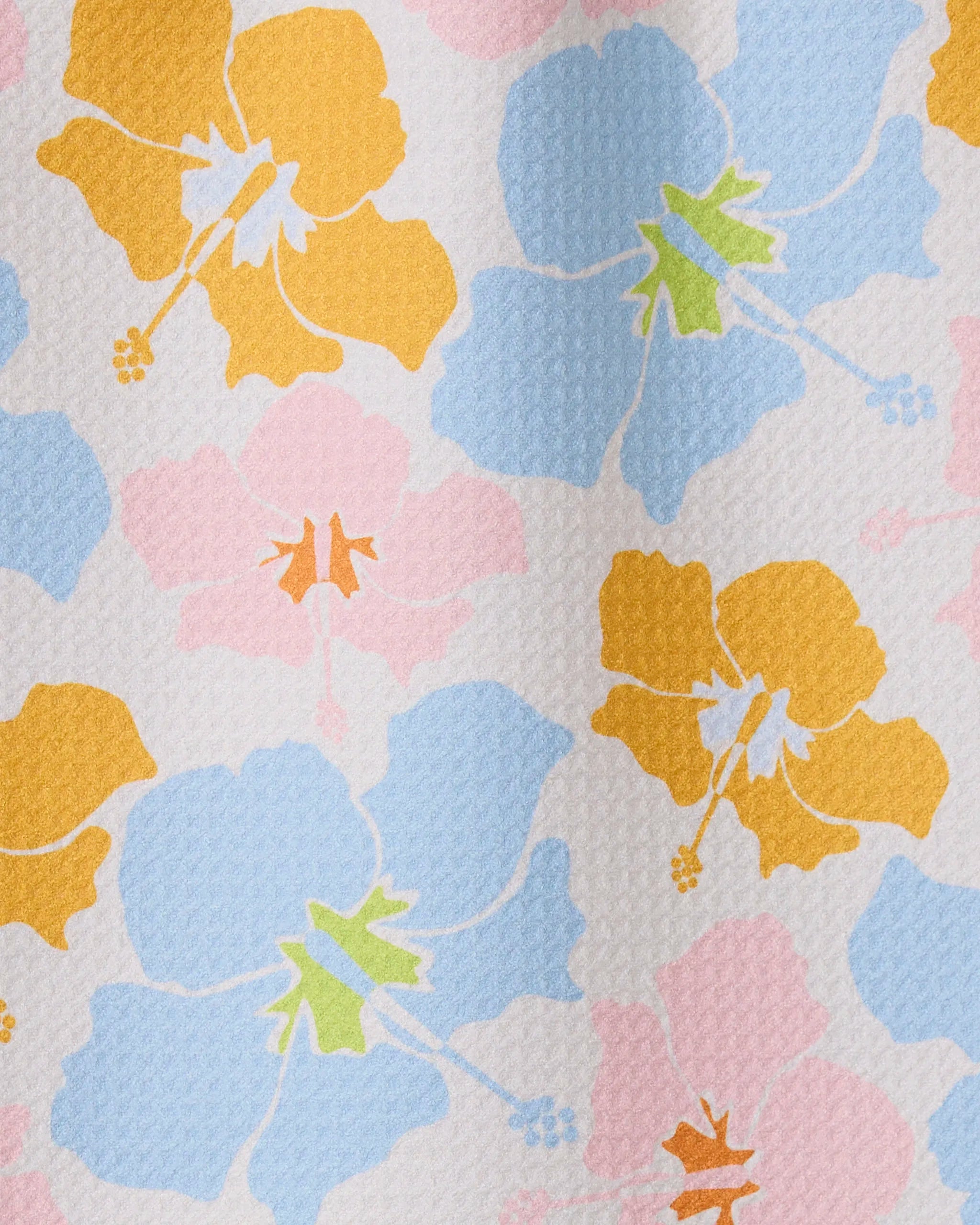 The GEOMETRY Hula Hues bar towel features a textured white background adorned with ultra-absorbent fabric and bold hibiscus flowers in yellow, blue, and pink with colorful centers.