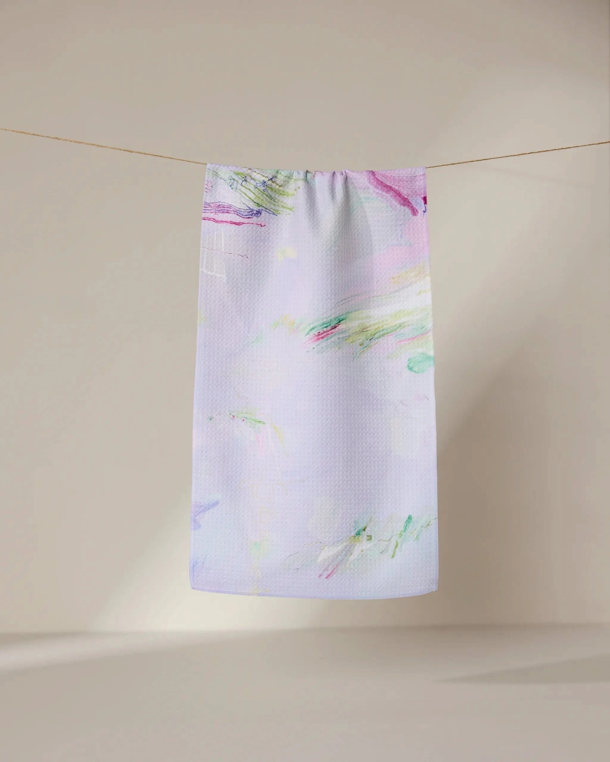 The GEOMETRY Province of Connacht bar towel features a pastel abstract watercolor design in purple, pink, green, and blue. Made from ultra-absorbent fabric, it hangs stylishly against a neutral background for both function and flair.