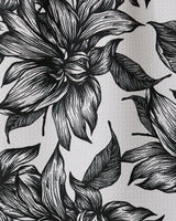 Black and white illustration of large, detailed flowers and leaves with intricate linework covers Caring by GEOMETRY, a textured recycled kitchen or bar towel.