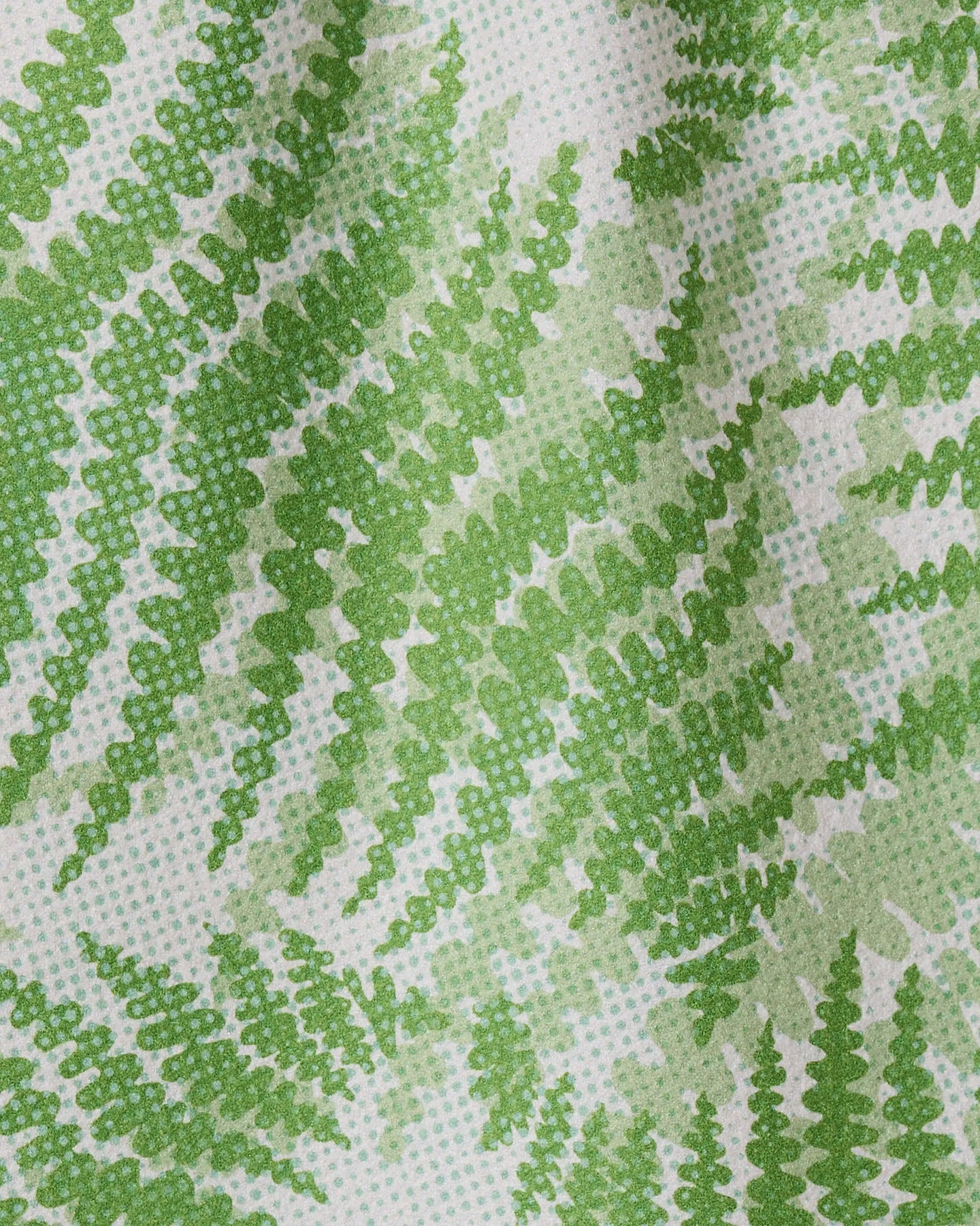 Close-up of the GEOMETRY Swaying Leaf quick-drying towel, featuring a white background with green fern leaves in varying shades, creating a textured and gently wavy design.