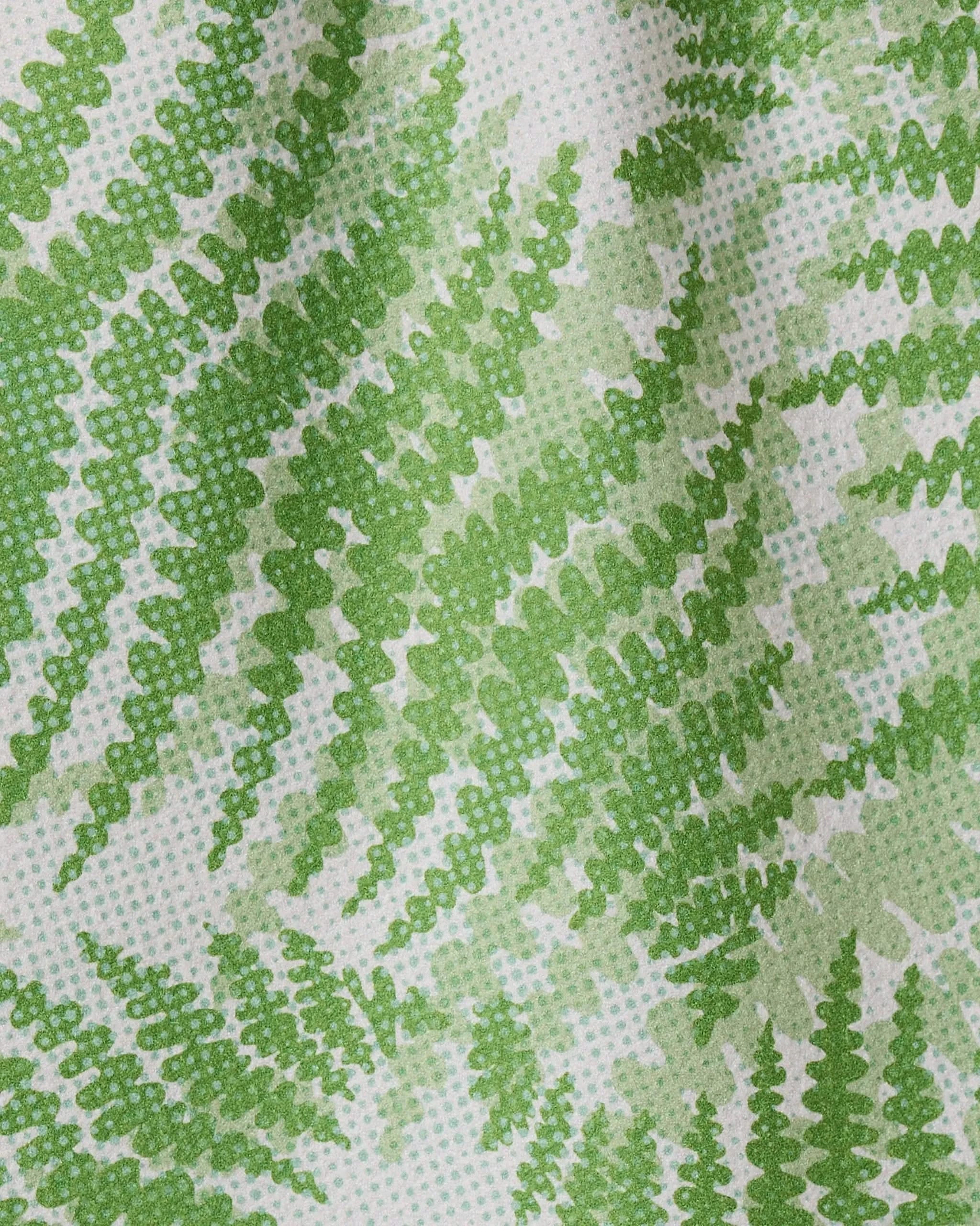 Close-up of the GEOMETRY Swaying Leaf quick-drying towel, featuring a white background with green fern leaves in varying shades, creating a textured and gently wavy design.