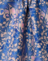 Close-up of Geometrys Lav tea towel, double-sided with a blue and light pink abstract butterfly or petal pattern, featuring intricate overlapping shapes and a soft, flowing texture.