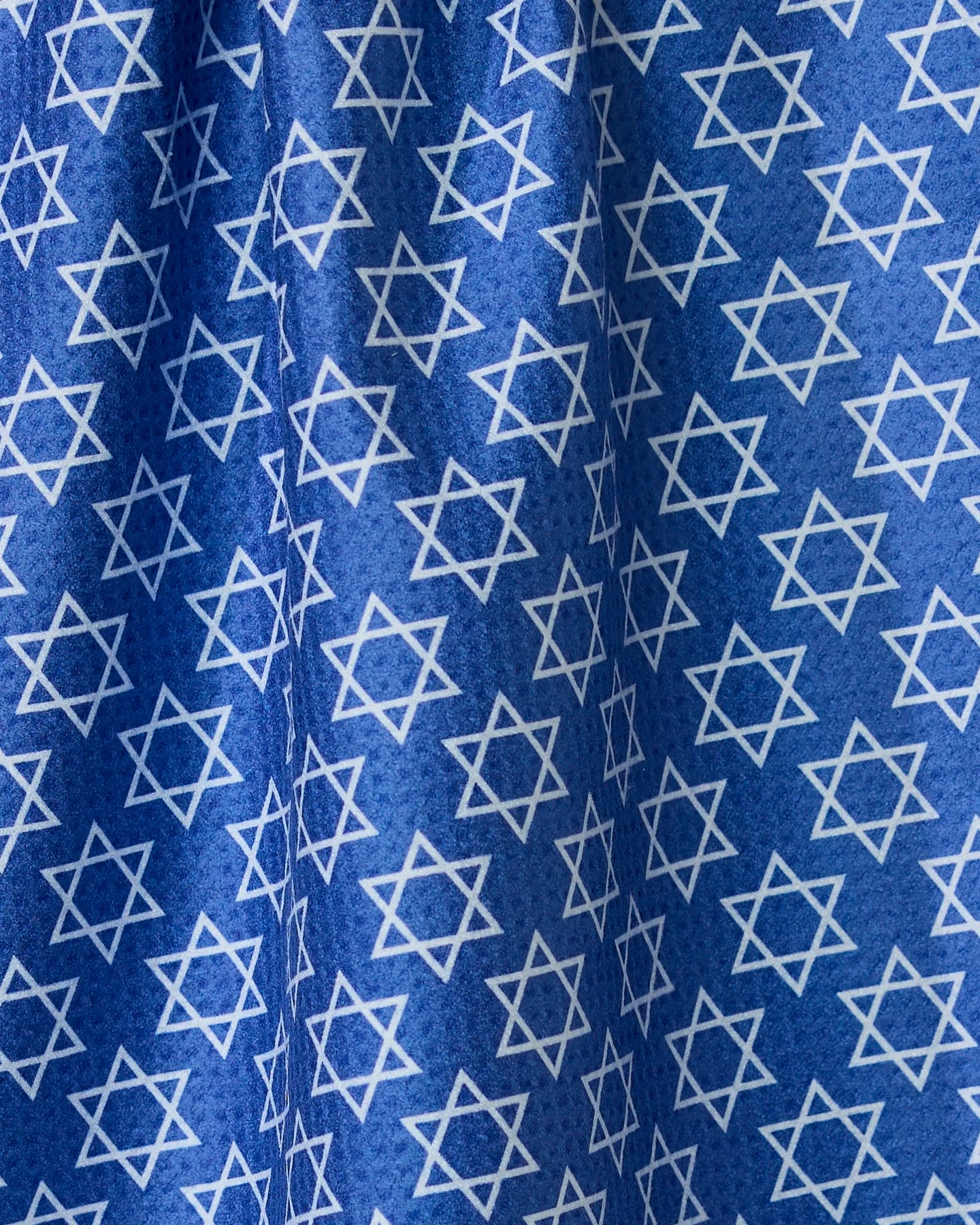 A blue double-sided tea towel from Geometry, called Star Of David, featuring an even pattern of white Stars of David. The fabrics folds and creases create varied light and shadow across the surface.