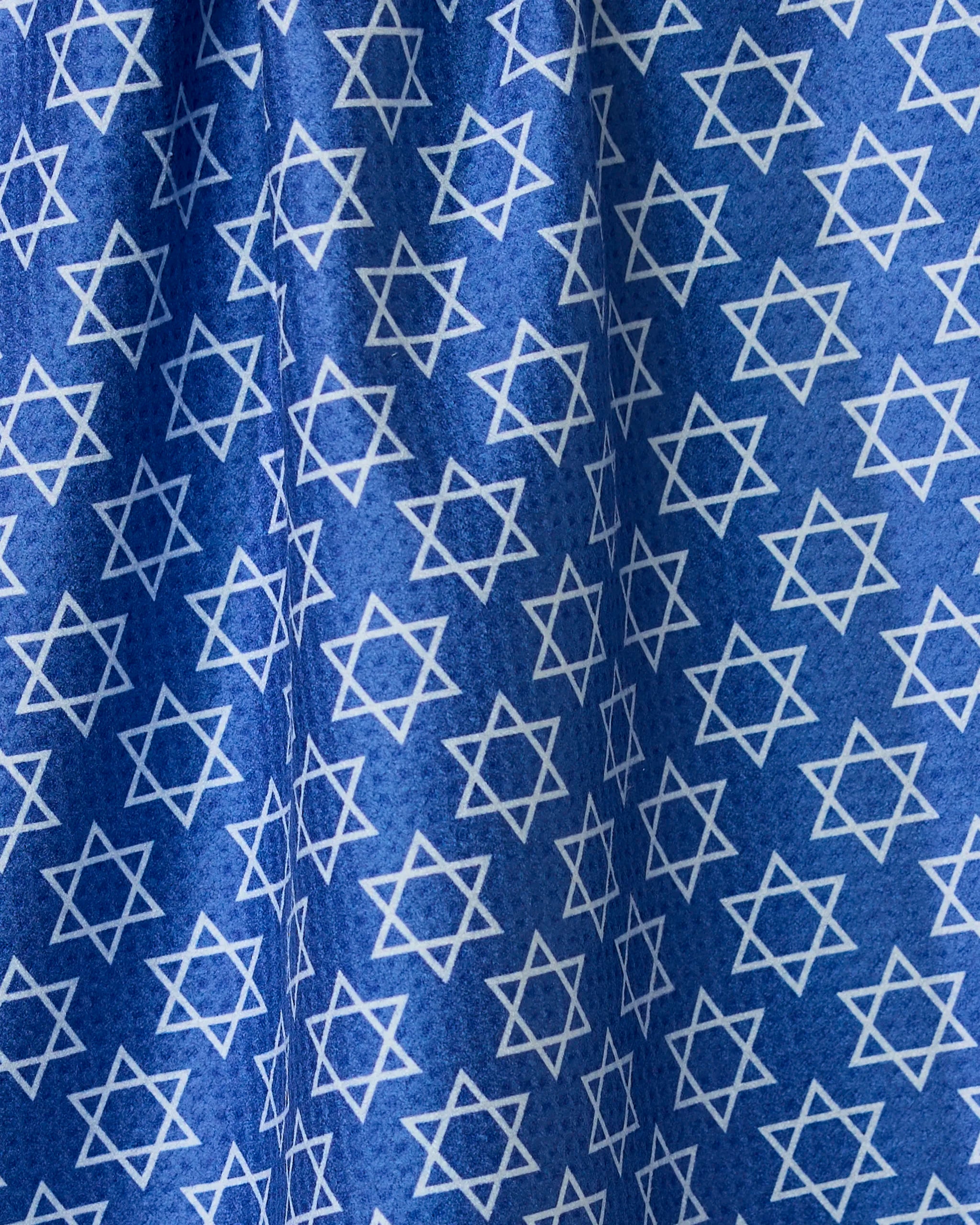 A blue double-sided tea towel from Geometry, called Star Of David, featuring an even pattern of white Stars of David. The fabrics folds and creases create varied light and shadow across the surface.