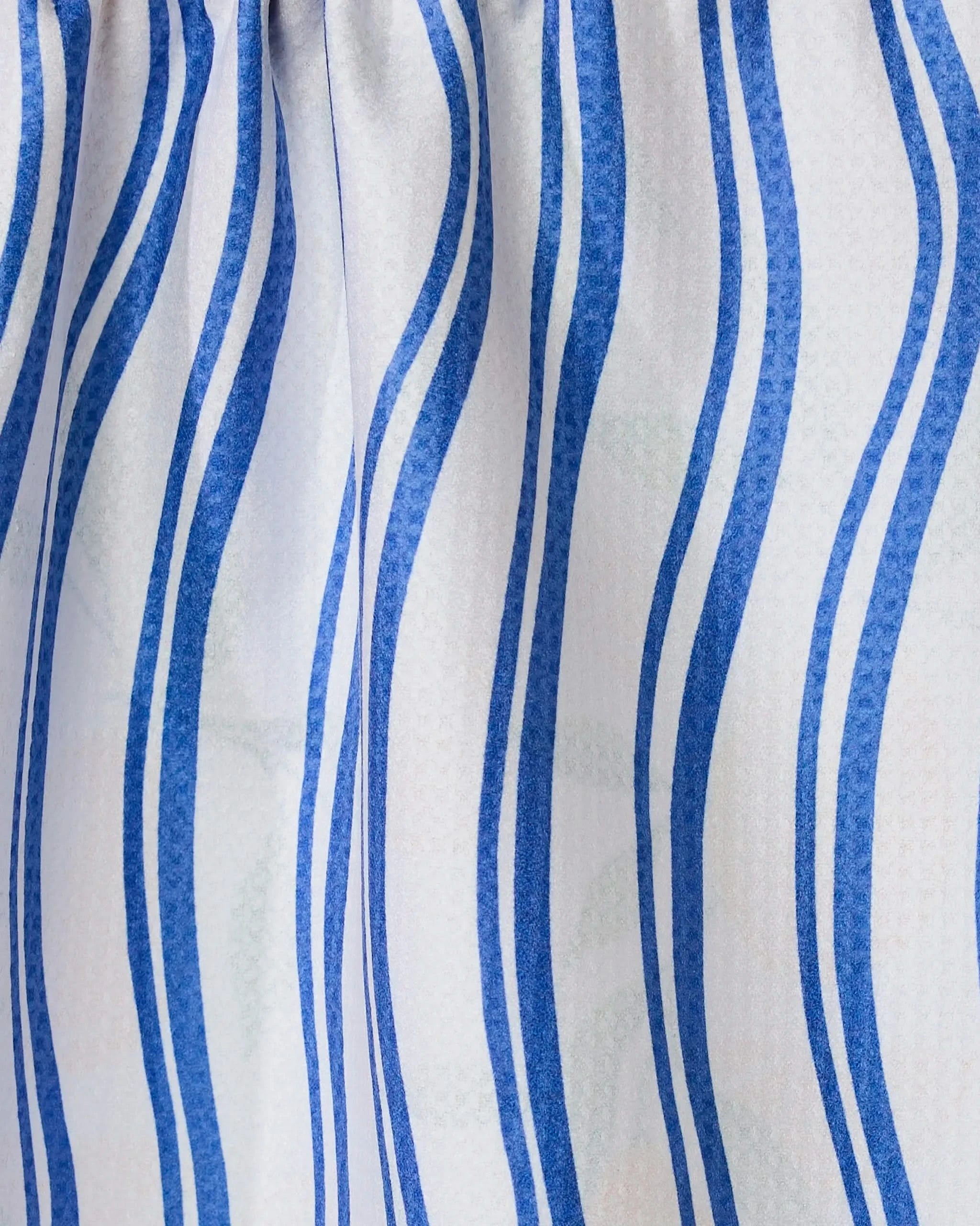 Close-up of Geometrys Lemon Bliss towel, featuring absorbent quick-drying fabric. Set against a white background, the towel has wavy vertical blue stripes and gentle gathers at the top, creating soft folds and shadows.