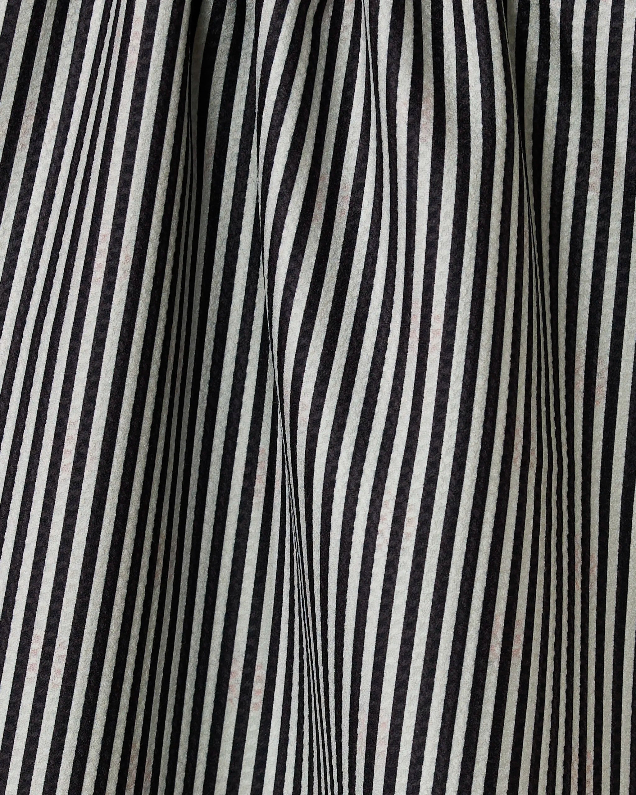 Close-up of black and white vertical stripes on the double-sided Lady tea towel by Geometry, showing folds and creases that create a wavy, textured pattern.