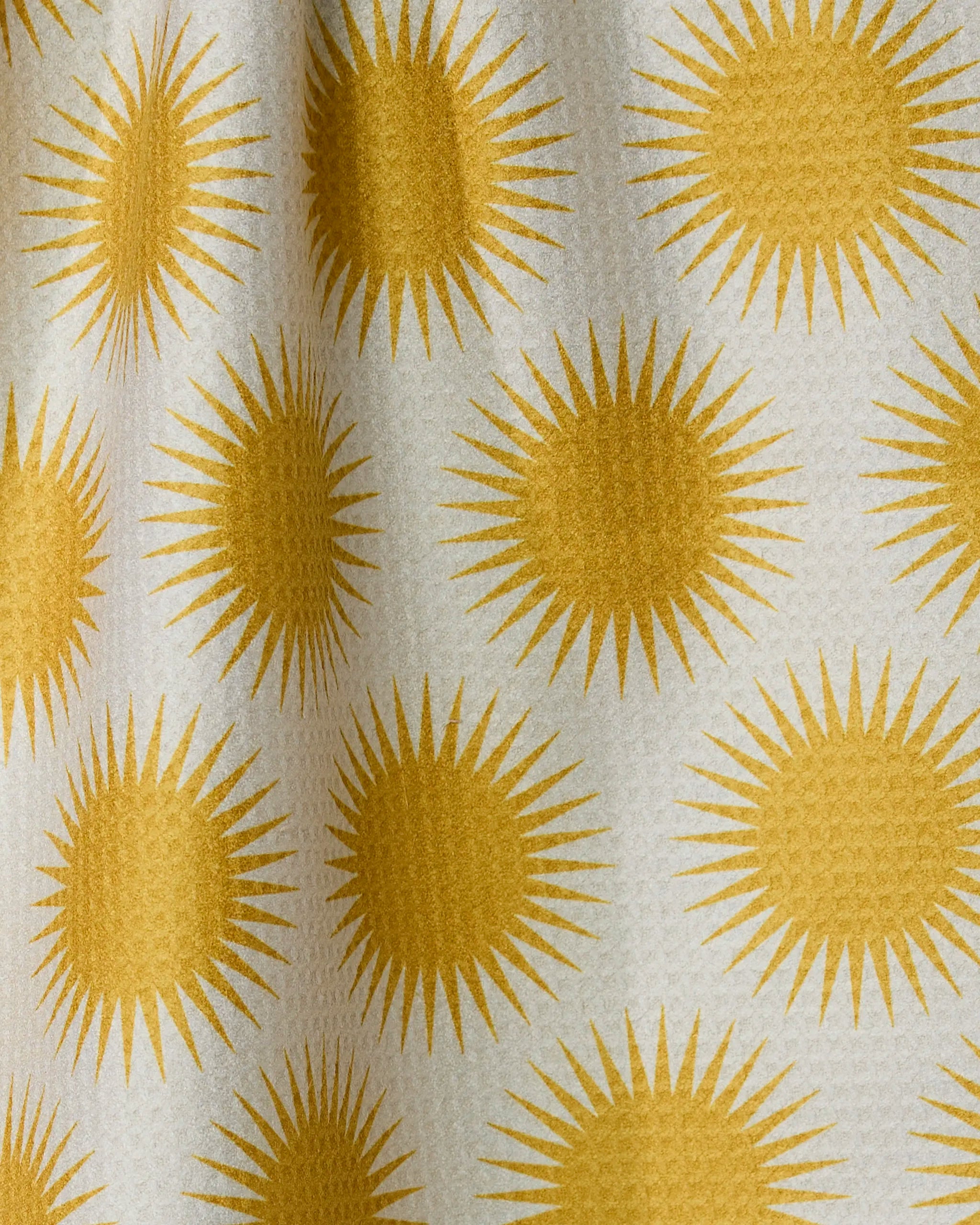 Radiating yellow suns repeat across a textured white fabric, giving depth and shadow to Geometry’s Energize absorbent quick-dry towel—perfect for brightening your kitchen.