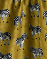 The Geometry Zebra Way tea towel is double-sided, featuring a mustard yellow background with a repeating pattern of black and white zebras in various poses and directions.
