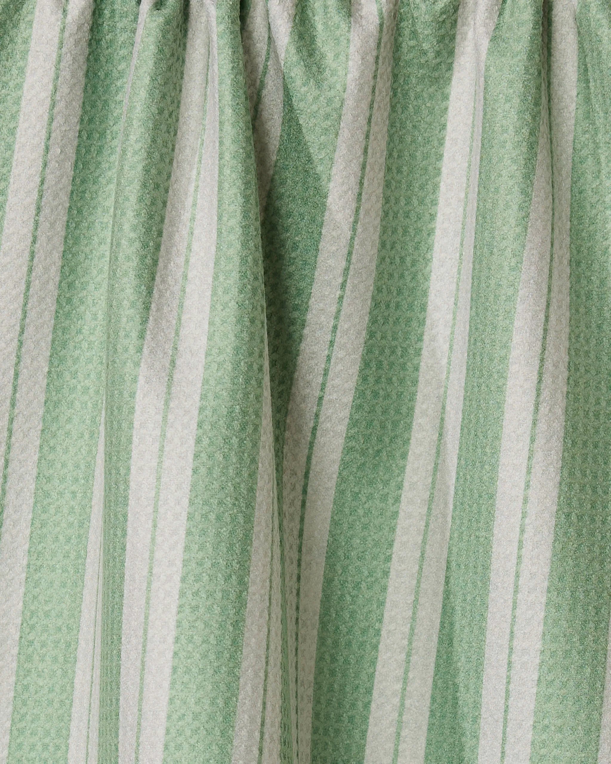 Close-up of Geometrys Pistachio recycled kitchen towel, featuring green and white vertical stripes in varying widths and a subtle texture, gathered at the top.