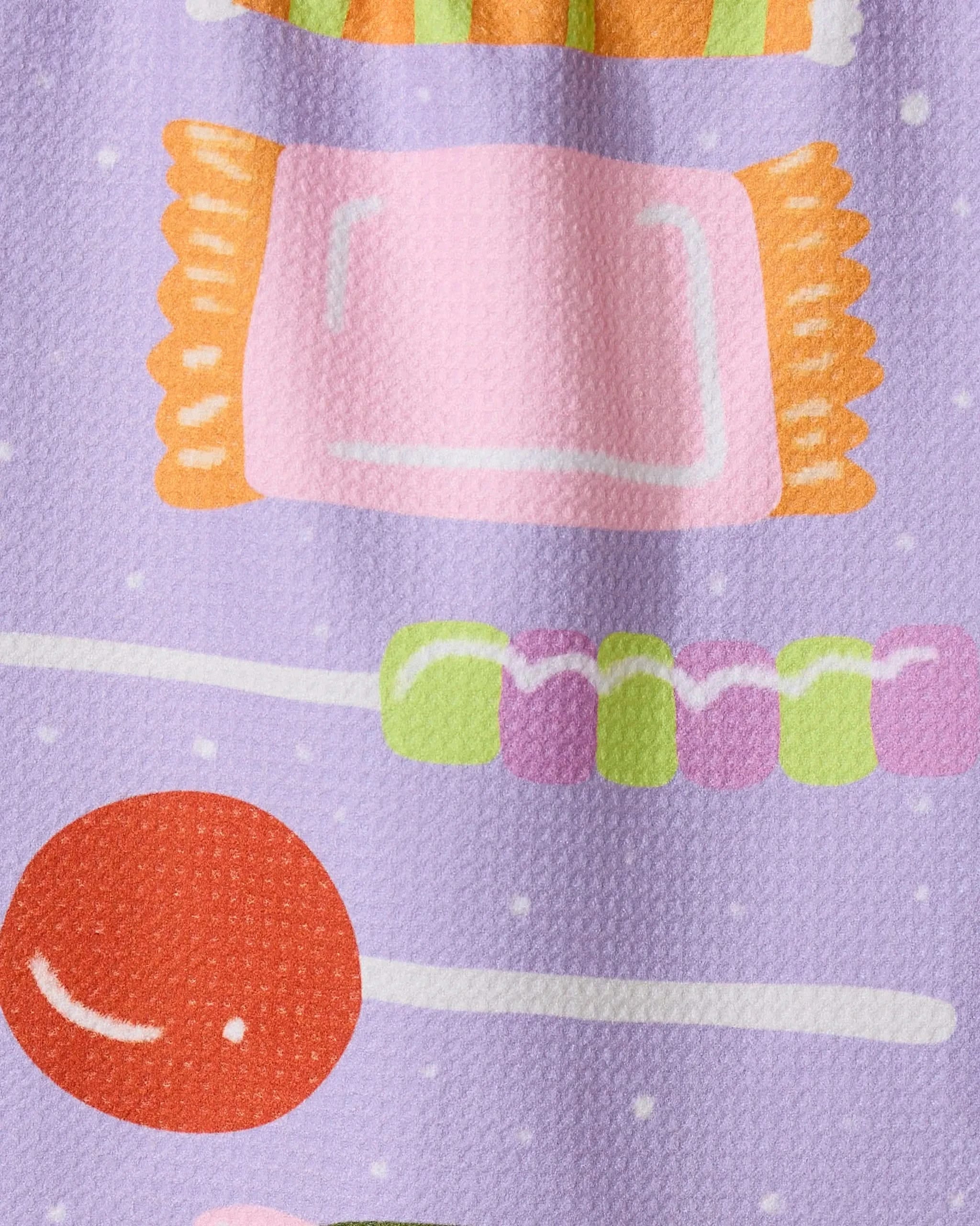 A close-up of the Geometry Stacked Sweet Treasures ultra-absorbent towel, featuring a colorful candy pattern with pink wrapped, green and pink round, and large red candies on a light purple textured background.