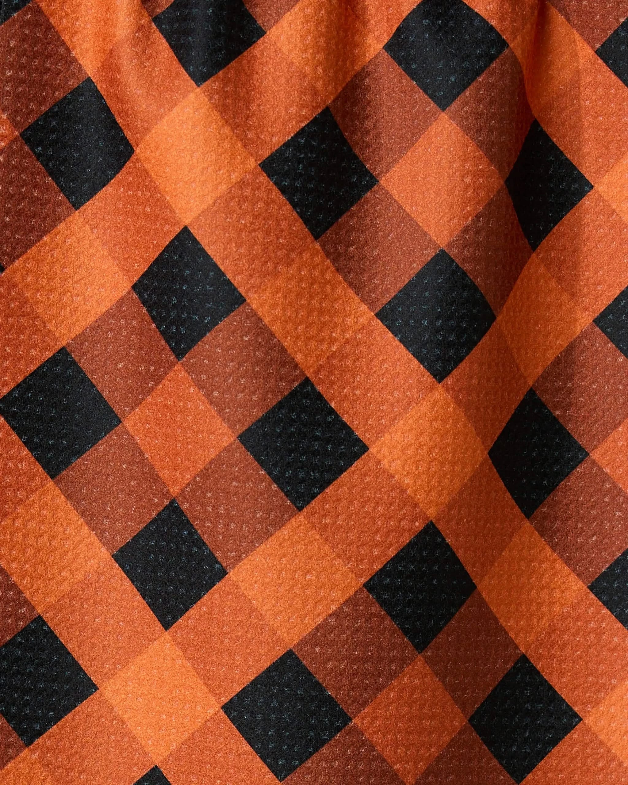 Close-up of Pumpkin Plaid by Geometry, featuring orange and black buffalo checks with a textured surface and soft folds—ideal for a recycled kitchen or bar towel.