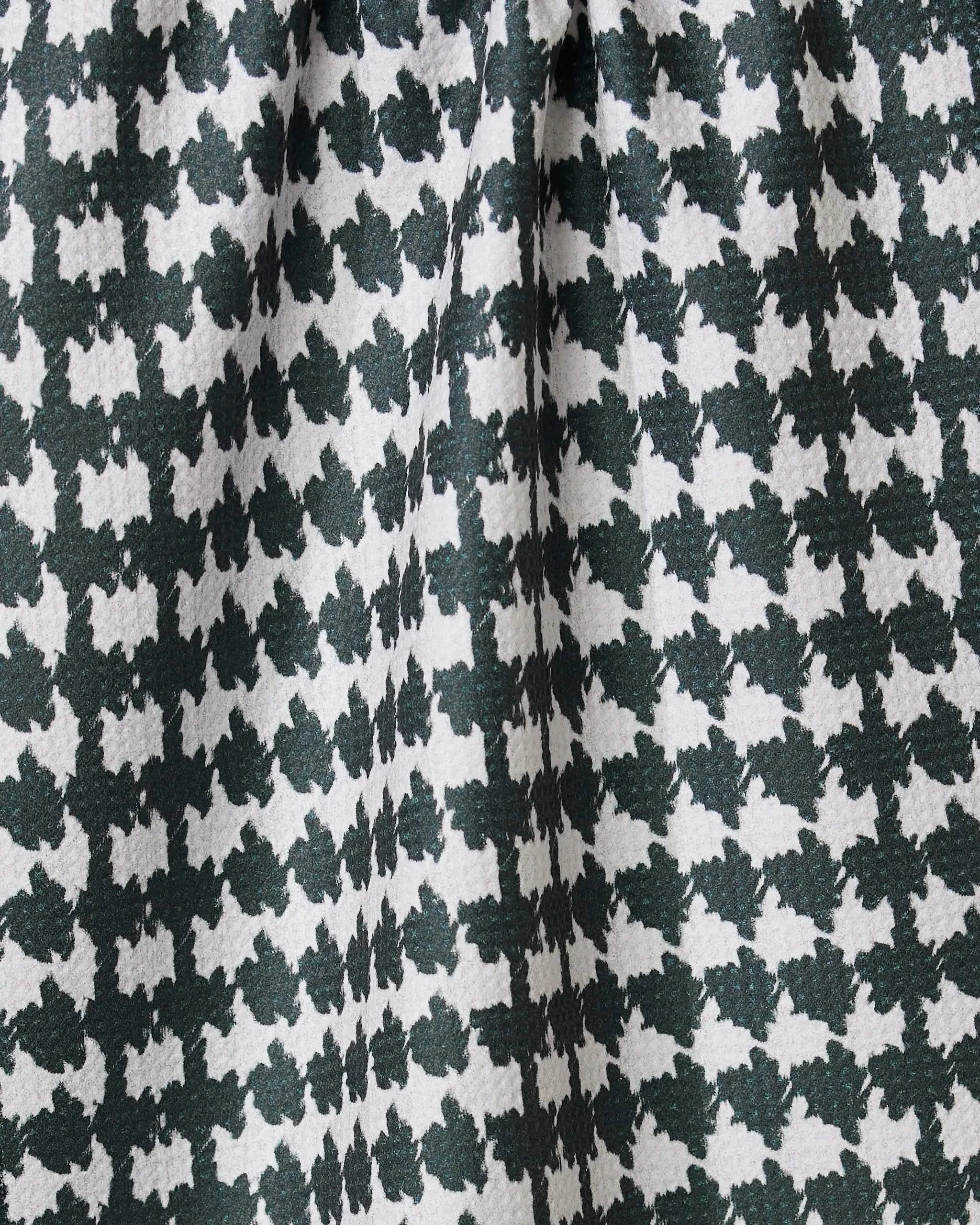 Close-up of Geometrys Electric Houndstooth Black tea towel, featuring a black and white houndstooth pattern made from recycled materials, with gathered folds adding depth and texture.