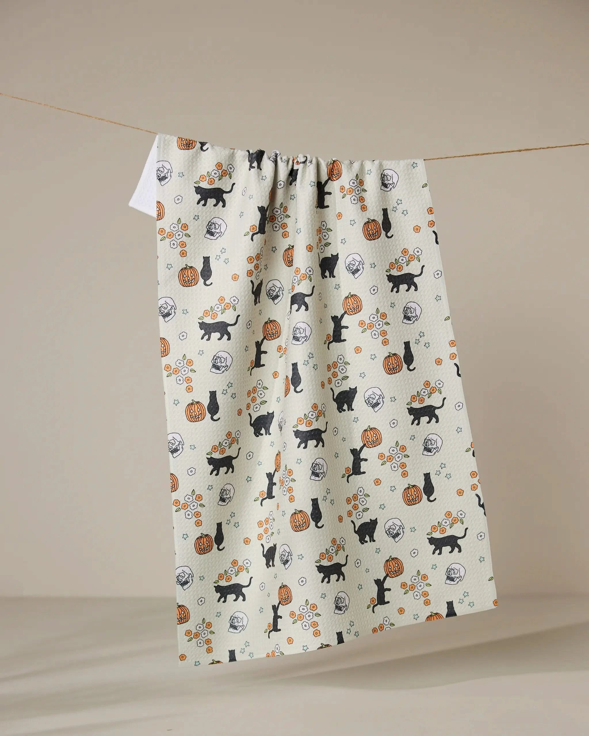 The Geometry “Spooky Parade” tea towel features black cats, pumpkins, and orange flowers on a cream background. Quick-drying and playful, it adds charm to your kitchen with its minimal neutral design.