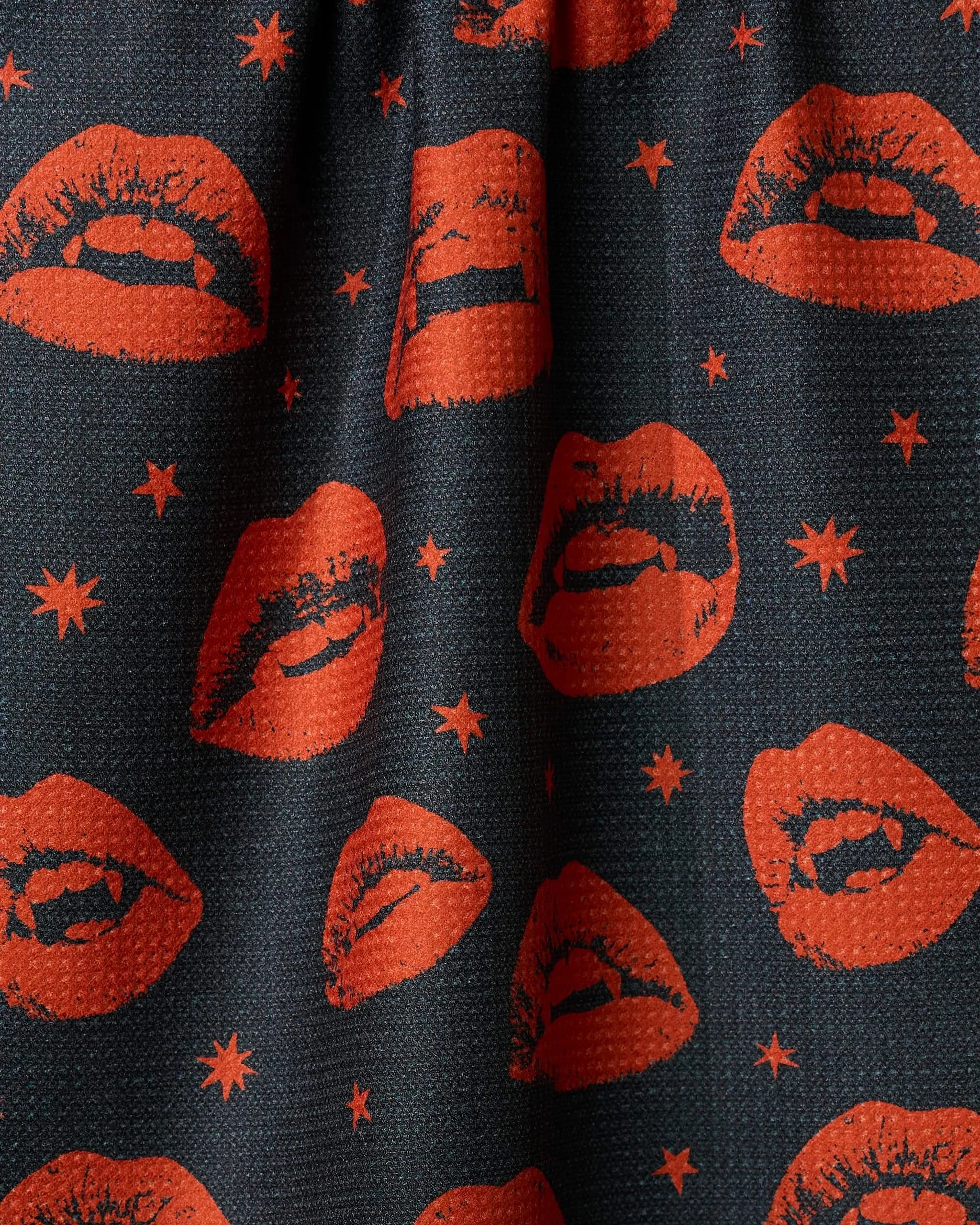 The Geometry Fangs tea towel features a black background with red lips—both open and closed—and small red stars in a repeating pattern, bringing playful charm to your kitchen.