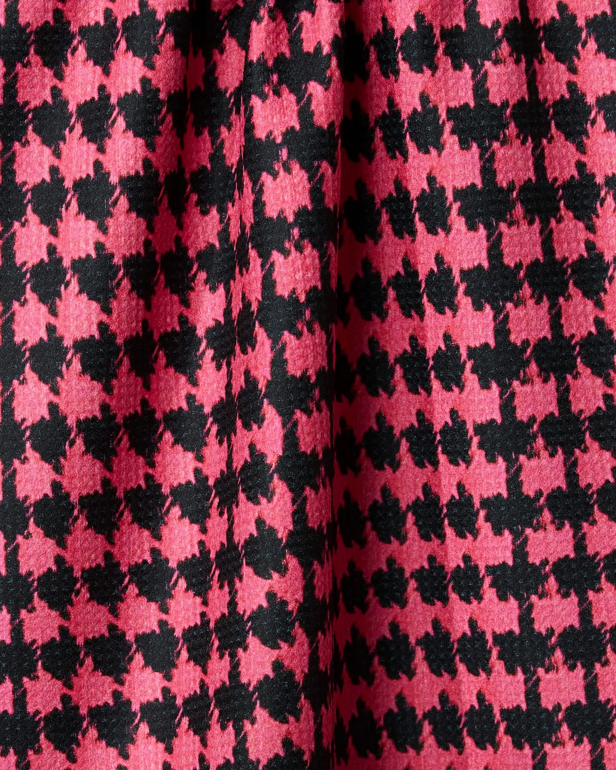 Close-up of Geometrys Electric Houndstooth fabric in pink and black, showing folds and shadows that highlight its stylish tea towel design.