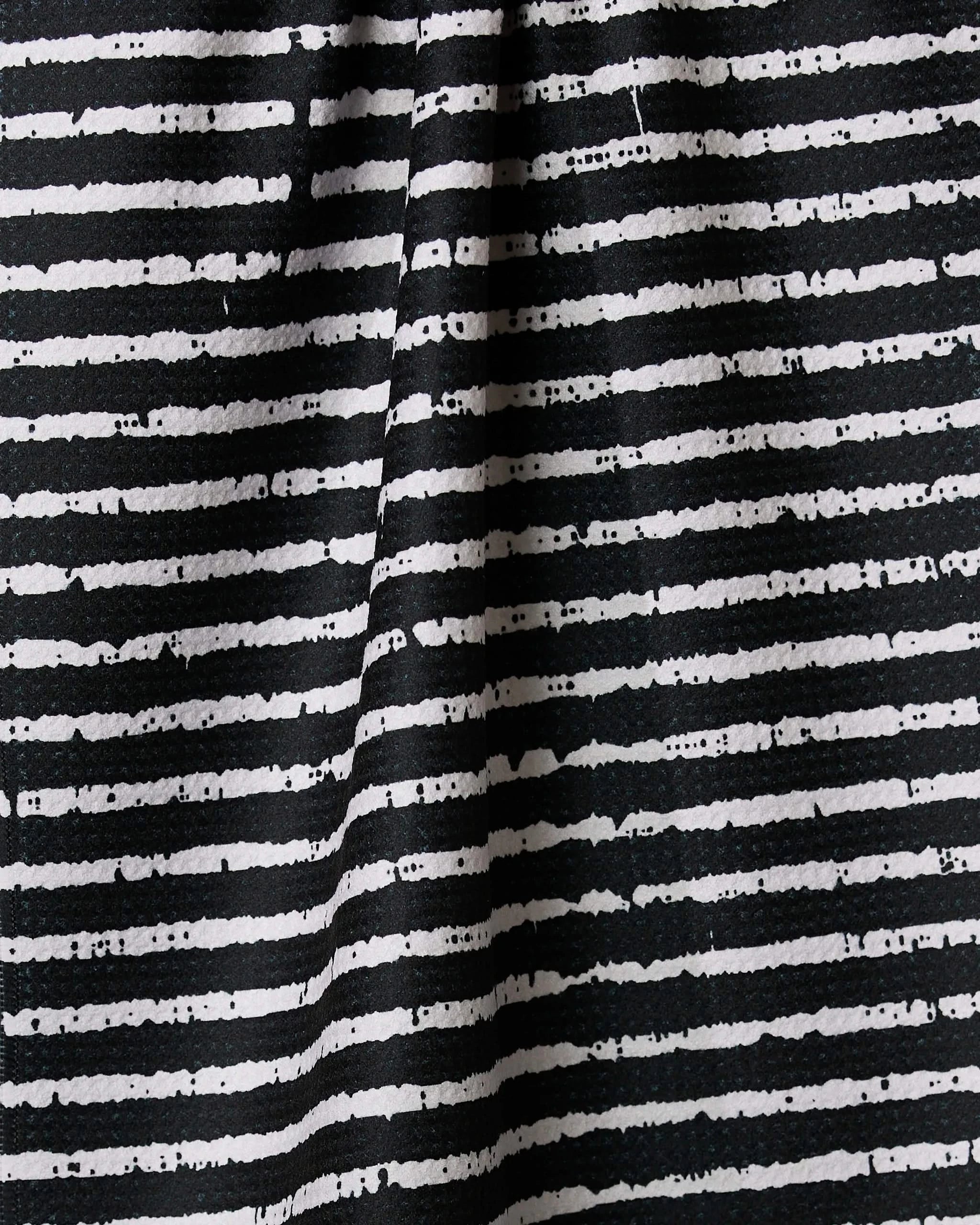 Close-up of Eerie Stripe by Geometry, a tea towel made from recycled materials. Features black and white uneven horizontal stripes with a hand-drawn look and visible fold, adding unique character to the textured fabric.