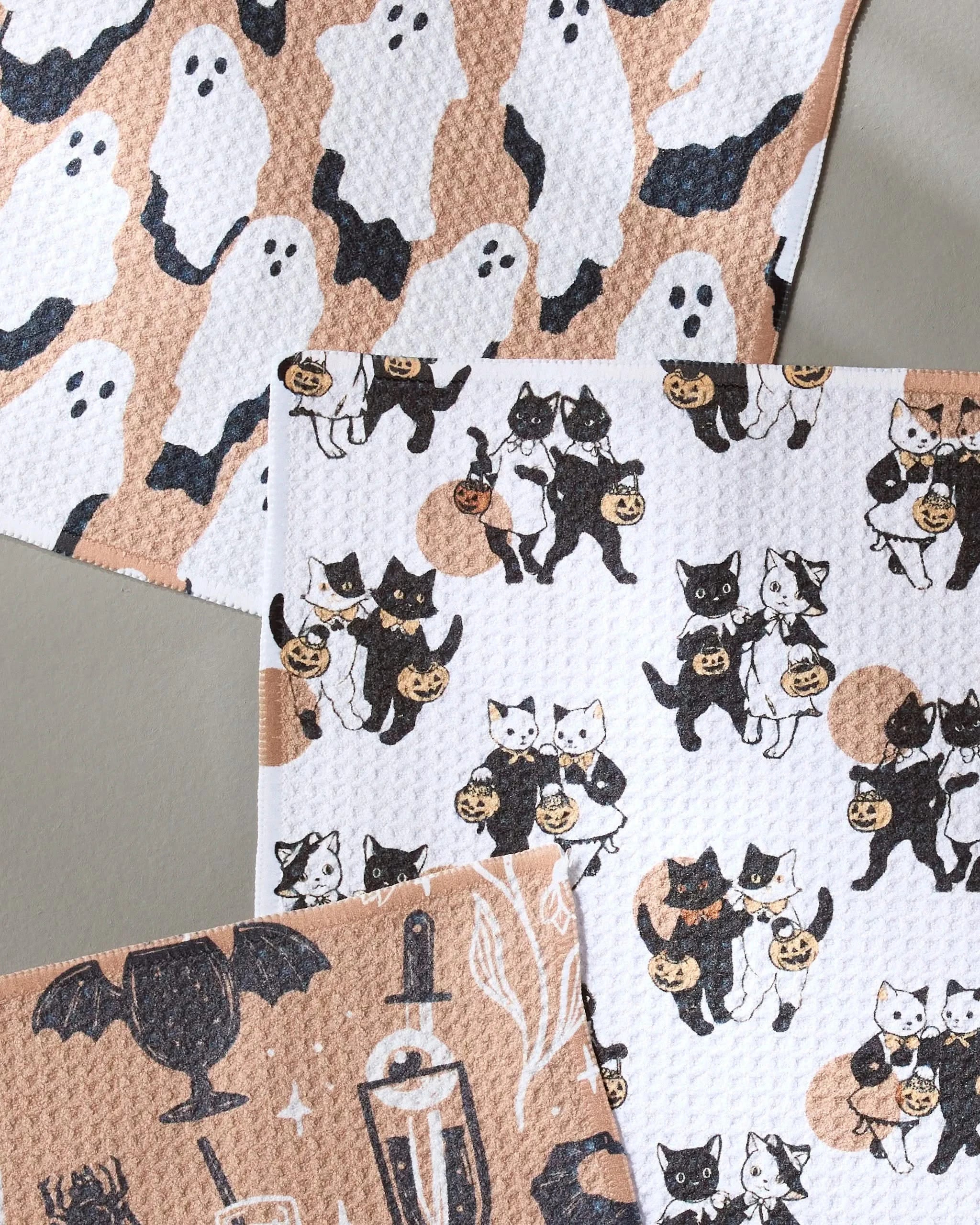 The Spooks dishcloth set by Geometry includes three patterned cloths: white ghosts, cats with jack-o’-lanterns, and black cats with pumpkins, bats, and Halloween drinks—all made from recycled materials.