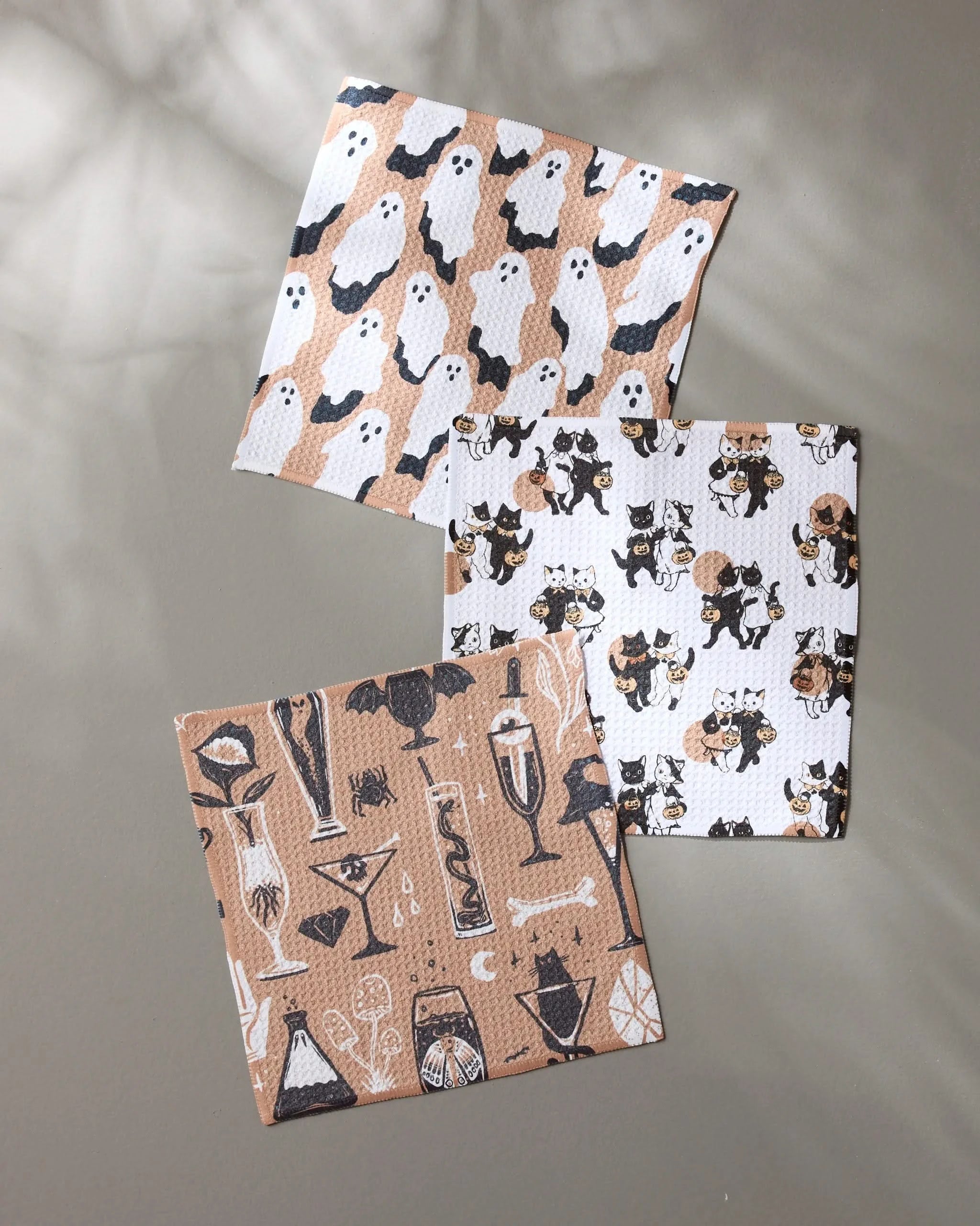 Geometrys Spooks set features three recycled dishcloths with festive Halloween prints—black and white cats, playful ghosts on tan, and spooky cocktails with bats—perfect for adding seasonal flair to your kitchen.