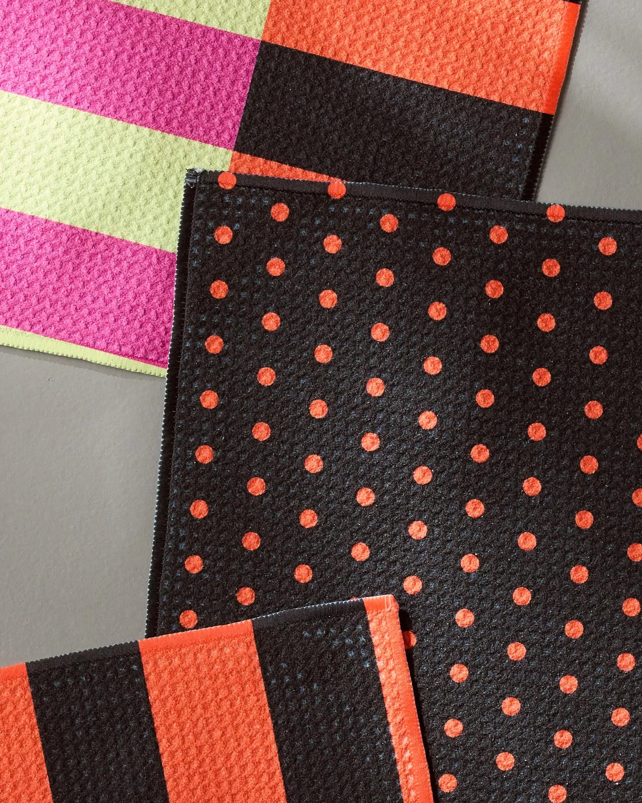 The Geometry Spooky Hour Stripe set includes four recycled dishcloths: one pink/yellow striped, one black/orange striped, and two black with orange polka dots—all featuring bold orange or red edges.