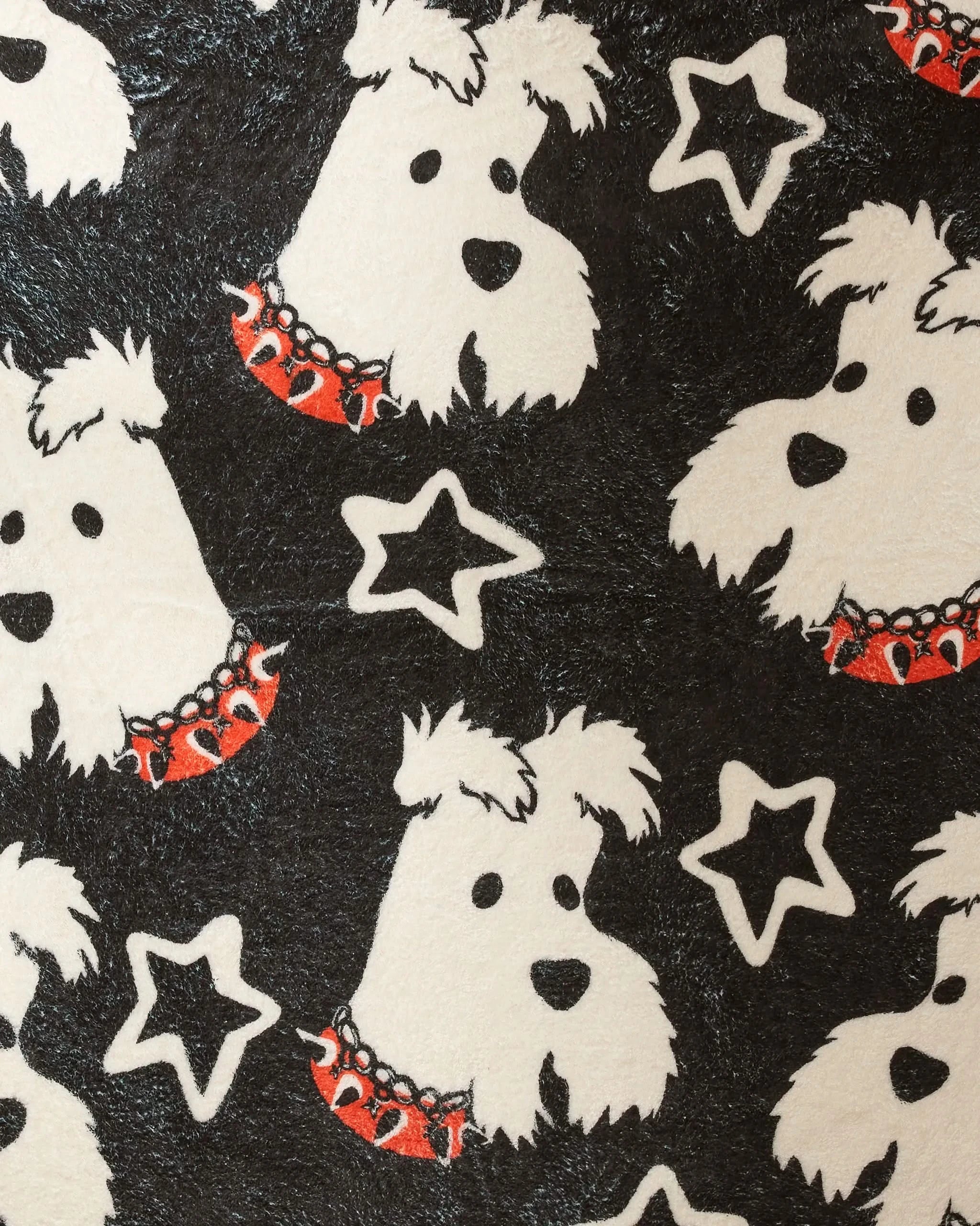 The Happy Howleen plush dog towel by Geometry features cartoon white dog faces with red spiked collars on a black background with white stars—combining style and function for your pup.