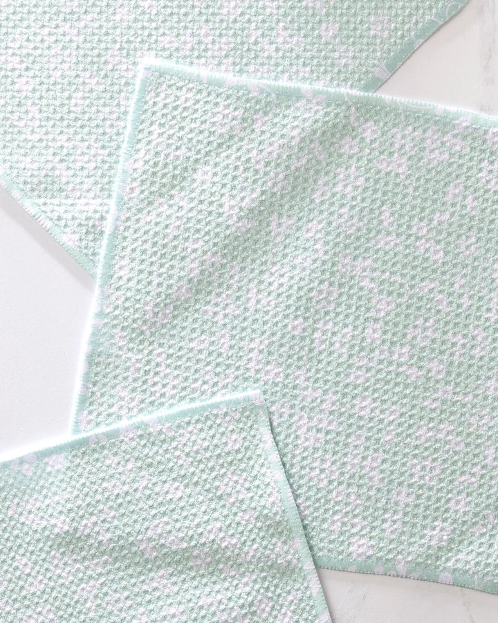 Three Dandy cleaning cloths by GEOMETRY, light green and white with a waffle-like texture and soft white patches, are arranged overlapping on a light surface—an eco-friendly kitchen choice in a reusable dishcloth set.