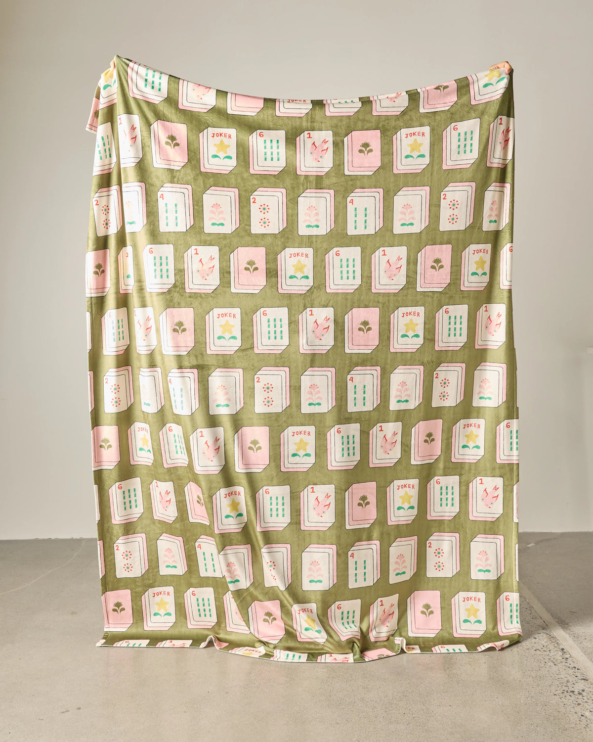 A silky soft, large green Geometry Flower Tiles Green Butter Blanket featuring a repeating pattern of mahjong tiles in shades of pink, white, and green.