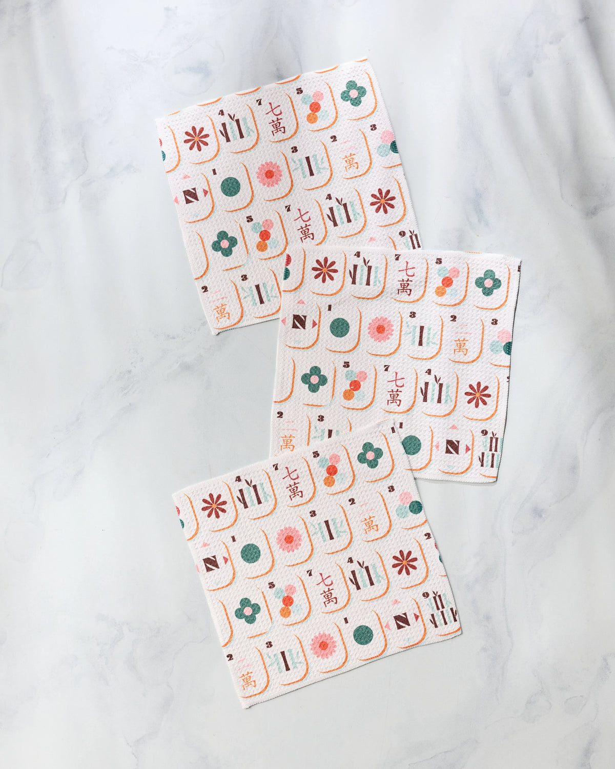 Three Cypress Tile Toss super-absorbent dishcloths featuring a repeating pattern of colorful mahjong tiles on a white background.