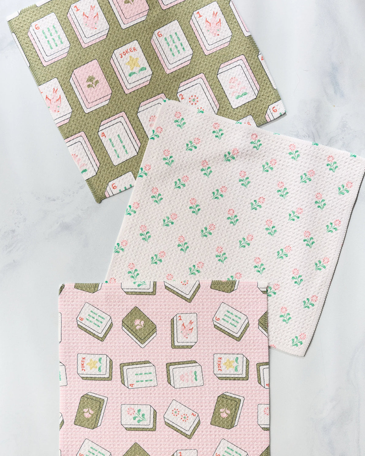 Three Geometry Flower Tiles super-absorbent dishcloths featuring two patterned mahjong tile designs in different colors and one with a small pink flower print.