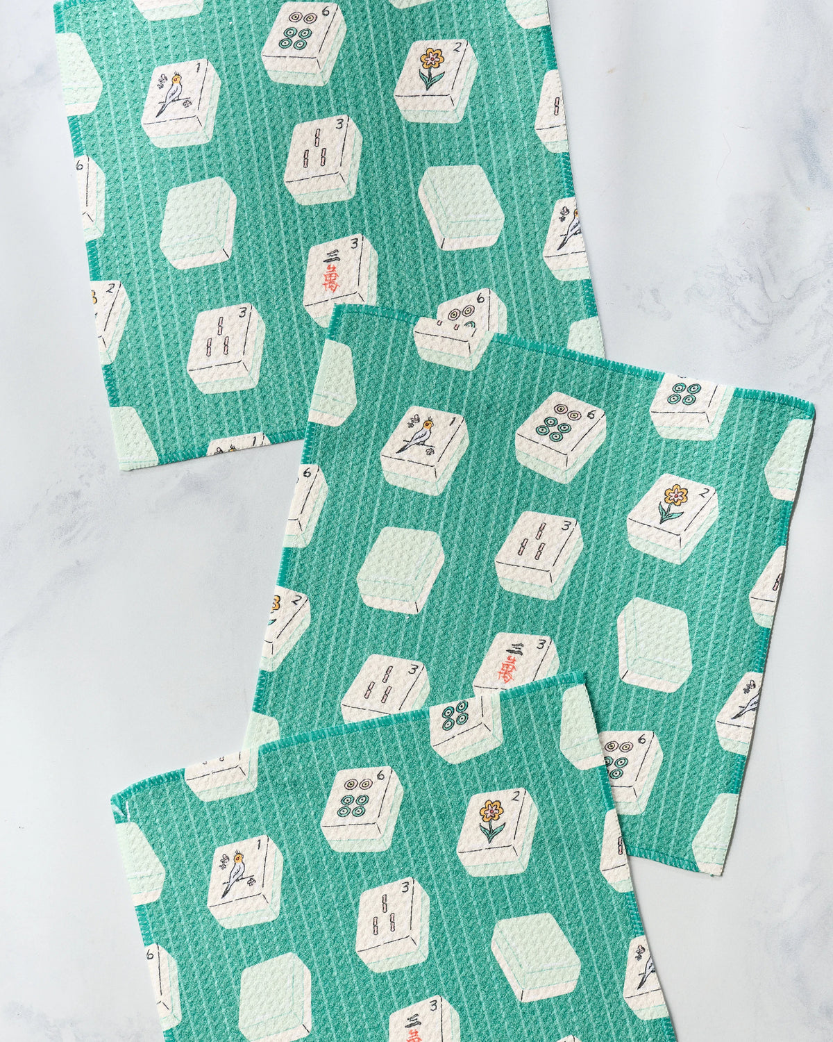 Three teal Geometry Tile Flow kitchen towels with a repeating pattern of mahjong tiles.