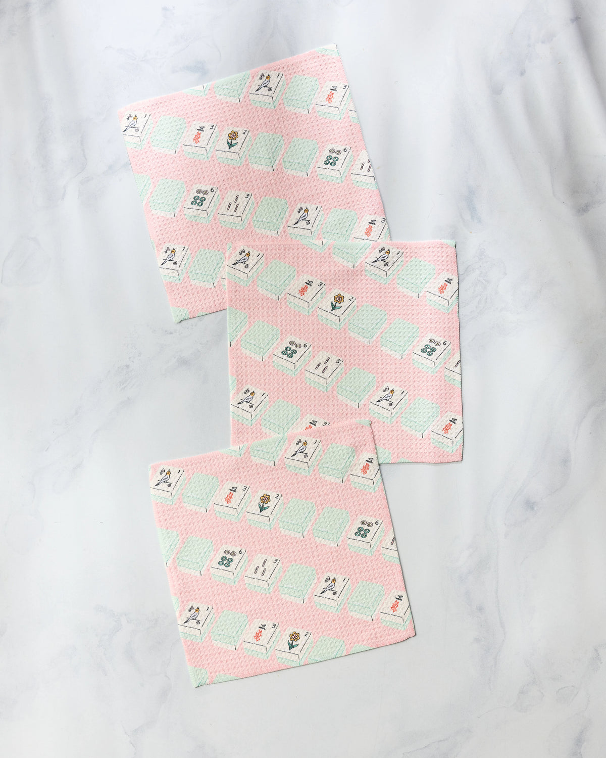 Three Tile Parade super-absorbent dishcloths with a light pink background featuring a repeating pattern of mahjong tiles.