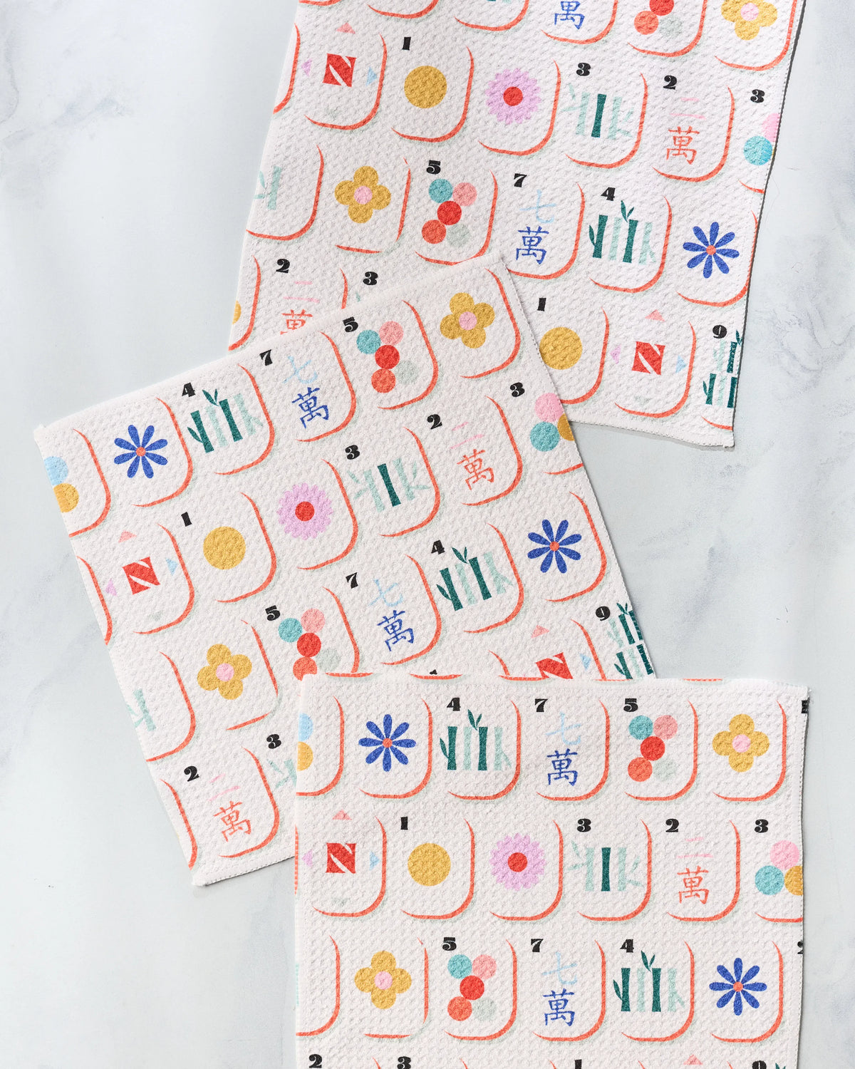 Three textured, super-absorbent Tile Toss dish towels featuring a repeating pattern of colorful Mahjong tiles.