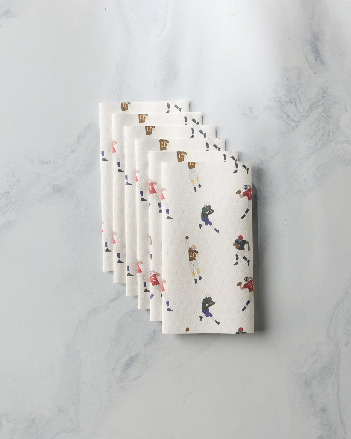 A stack of five folded, eco-friendly Geometry Roster reusable paper towels featuring an all-over print of football players in various uniforms.