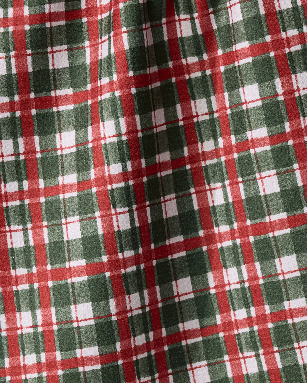 The Geometry Alpine Plaid dish towel features a red, green, and white plaid design with intersecting lines and a textured, slightly wrinkled look that enhances its absorbent quality.