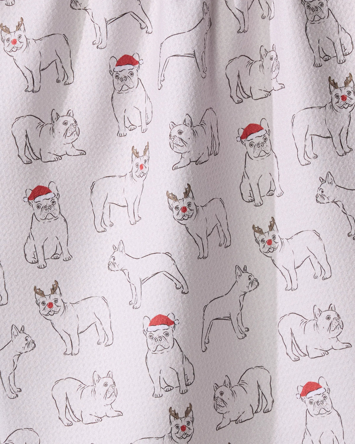 The Geometry Festive Frenchies tea towel features line-drawn bulldogs—some with red Santa hats or antlers and red noses, others plain—on a white background.
