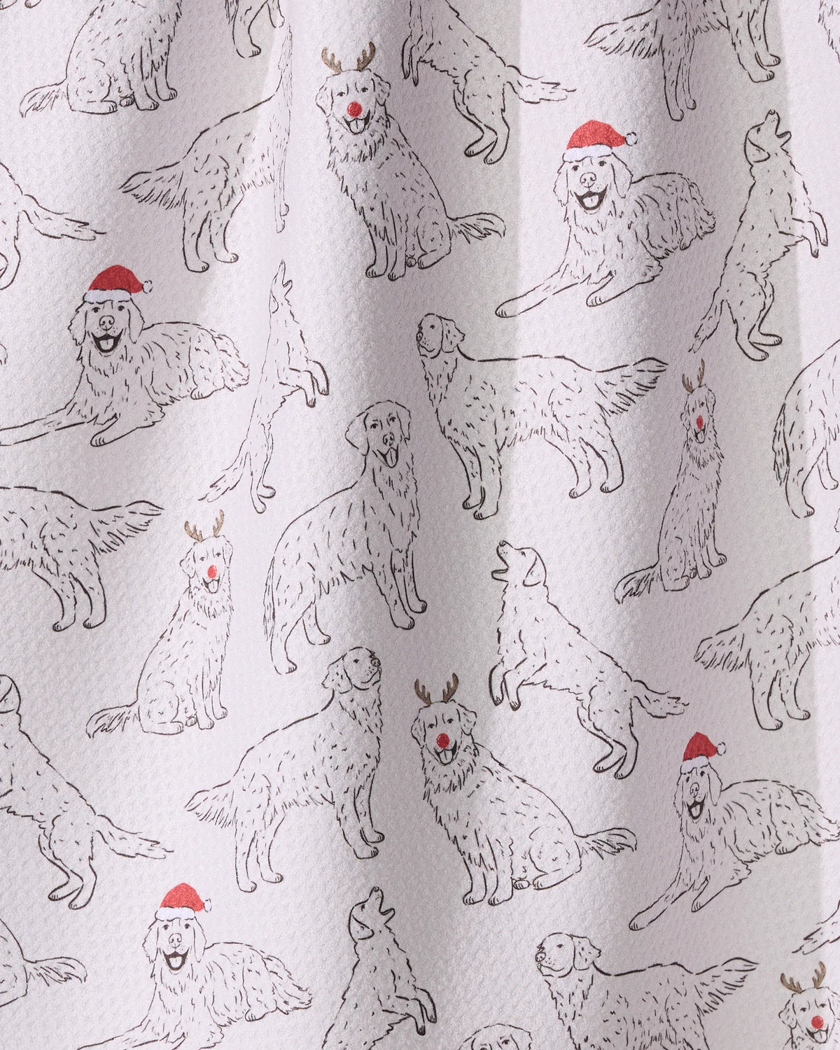 Geometry’s Festive Goldens tea towel features a repeating pattern of dogs in Santa hats and reindeer antlers, all on white textured fabric made from recycled materials.