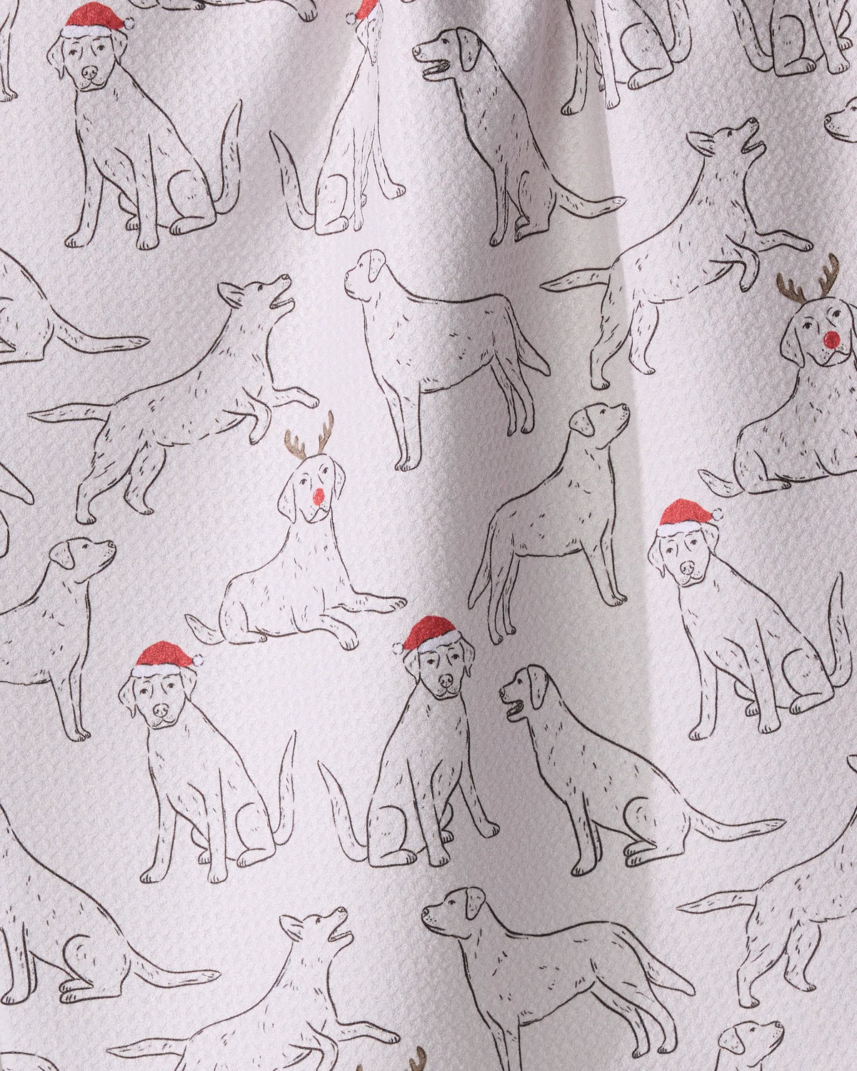 The Geometry Festive Labs kitchen towel features line drawings of dogs in holiday poses, with some wearing Santa hats or antlers. Made from recycled materials.