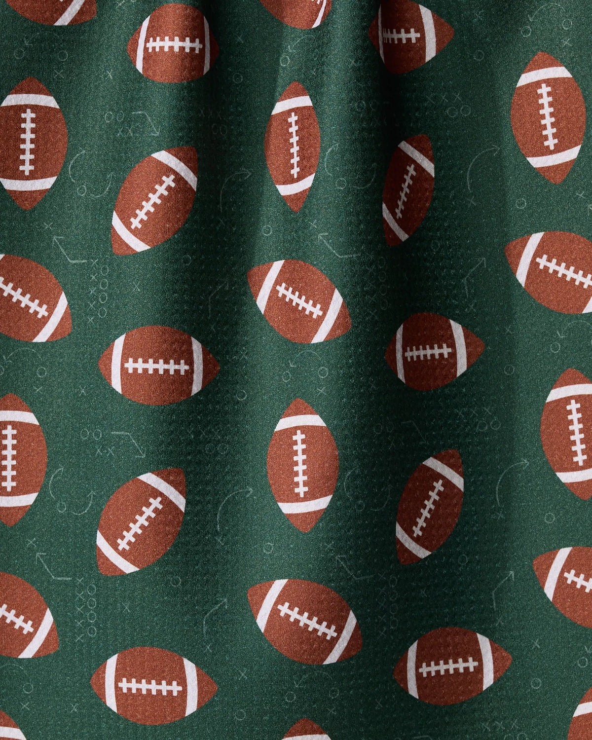 Geometry First Down recycled kitchen towel in dark green with a repeating print of brown footballs and faint white play diagrams.