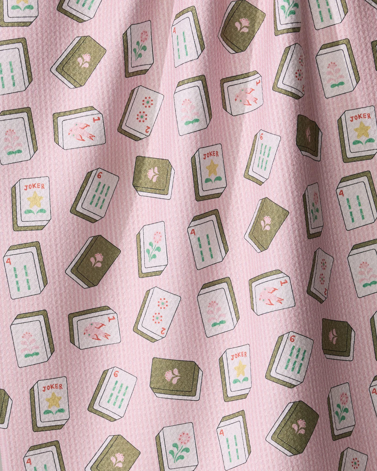 Flower Tiles kitchen towel in pink recycled fabric patterned with scattered mahjong tiles featuring flower designs, numbers, and Joker labels.