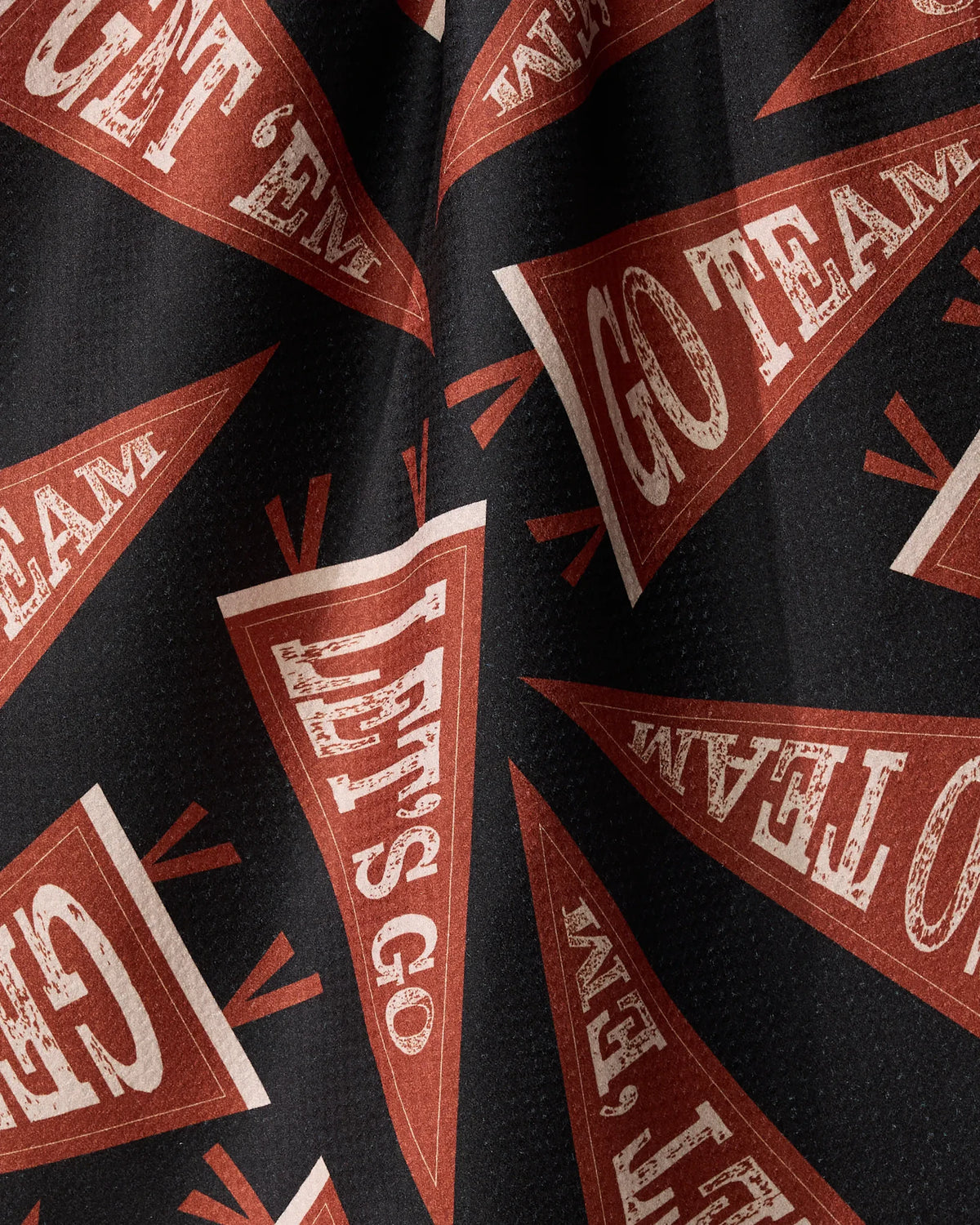 Black eco-friendly Football Chant tea towel featuring a repeating pattern of triangular red pennants with the weathered text Lets Go and Go Team.