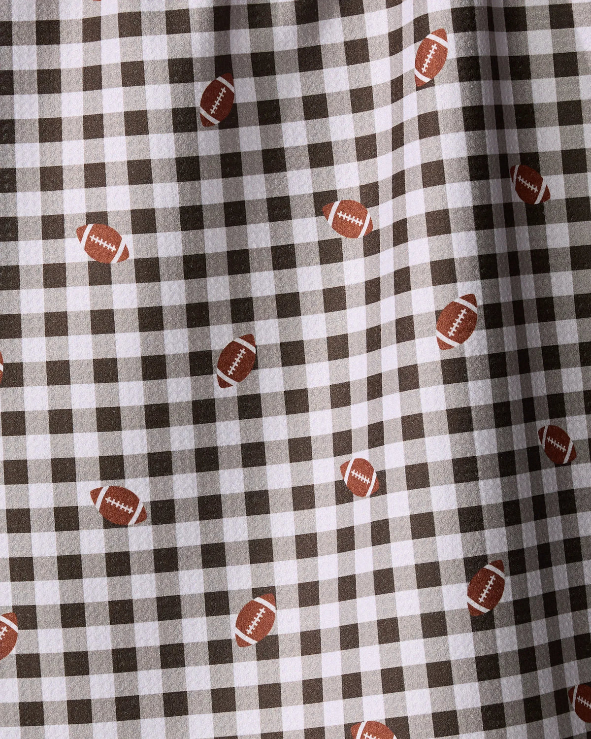 Geometry Football Check tea towel in a black and white gingham pattern with small brown footballs.