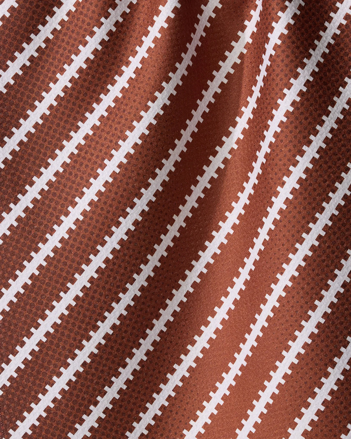 Geometry Laces Out is an ultra-absorbent brown tea towel featuring a repeating pattern of white diagonal stripes resembling football laces.
