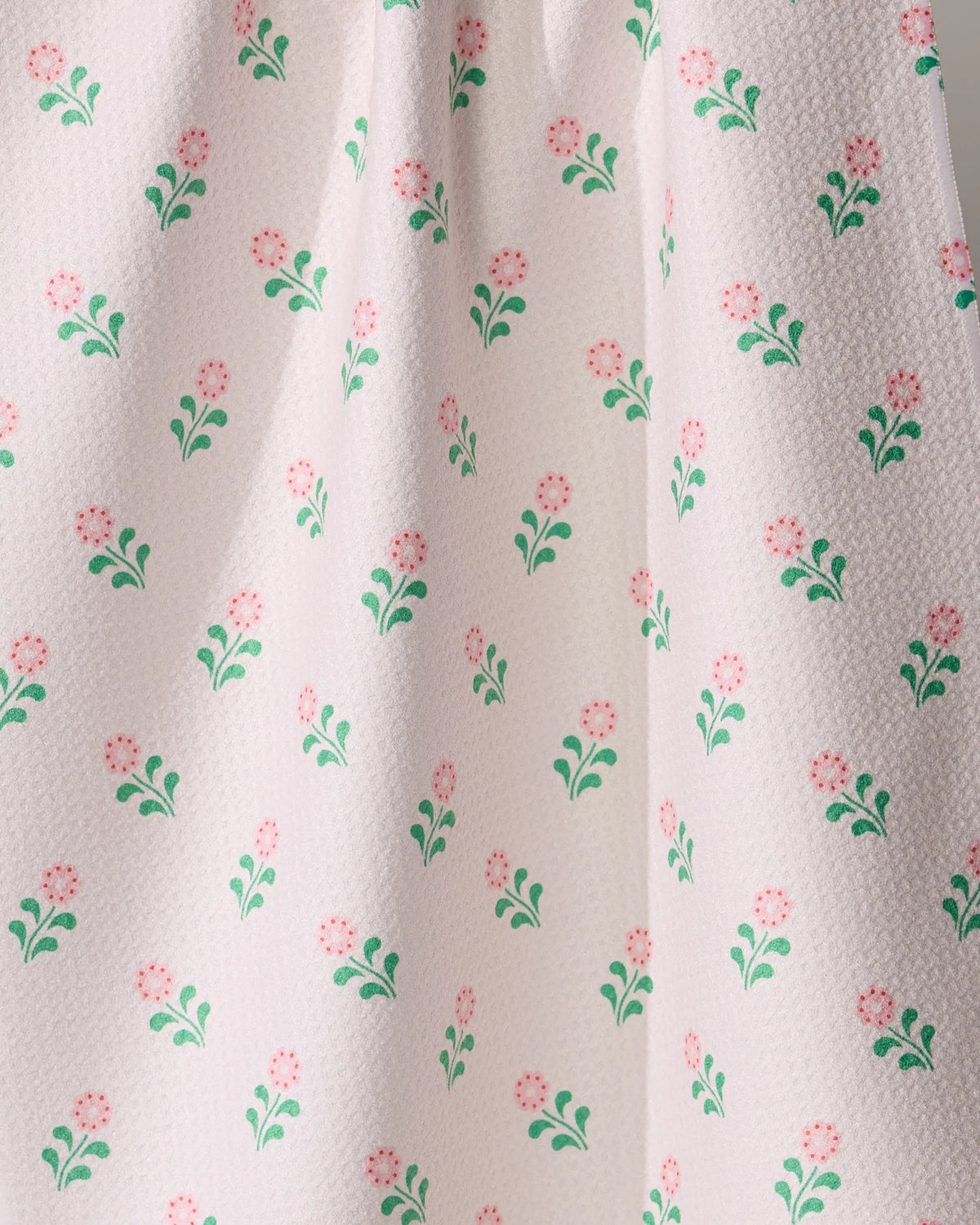 Geometry Lucky Blossom kitchen tea towel in white with a repeating pattern of small pink flowers, green stems, and leaves.