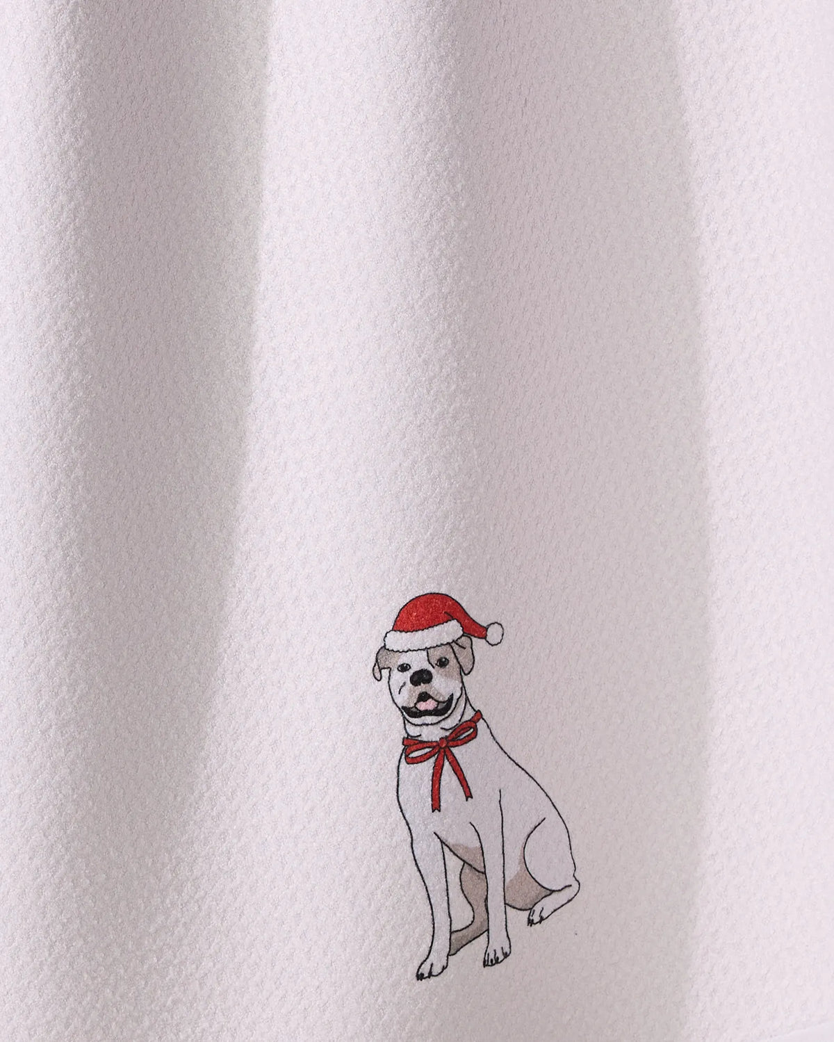 The Geometry “Merry Bulldog” features a white dog in a red Santa hat and bow, sitting on a textured white background—ideal for a festive tea towel made from recycled materials.