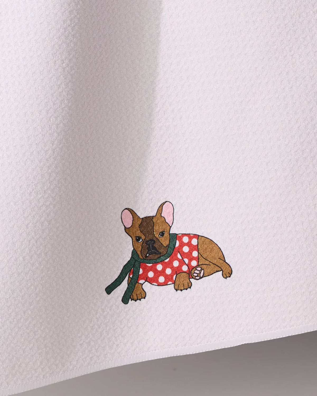 Merry Frenchie by Geometry features a small embroidered dog in a red polka-dot sweater and green scarf on an ultra-absorbent white tea towel made from recycled materials.