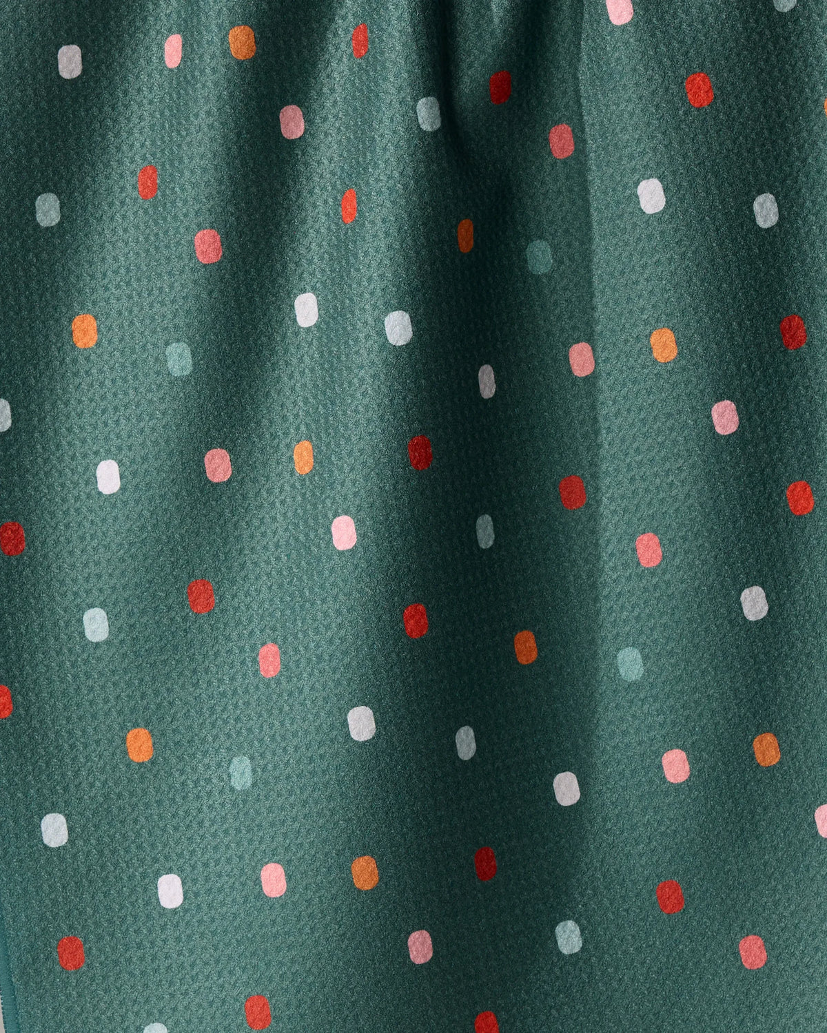 Moss Tile Shuffle tea towel in dark green fabric patterned with a repeating grid of small, rounded rectangles in shades of white, pink, and orange.