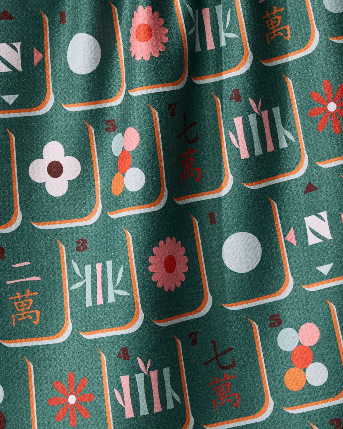 Moss Tile Toss quick-drying green fabric featuring a repeating pattern of mahjong tiles with red, pink, and white floral, numeric, and geometric designs.