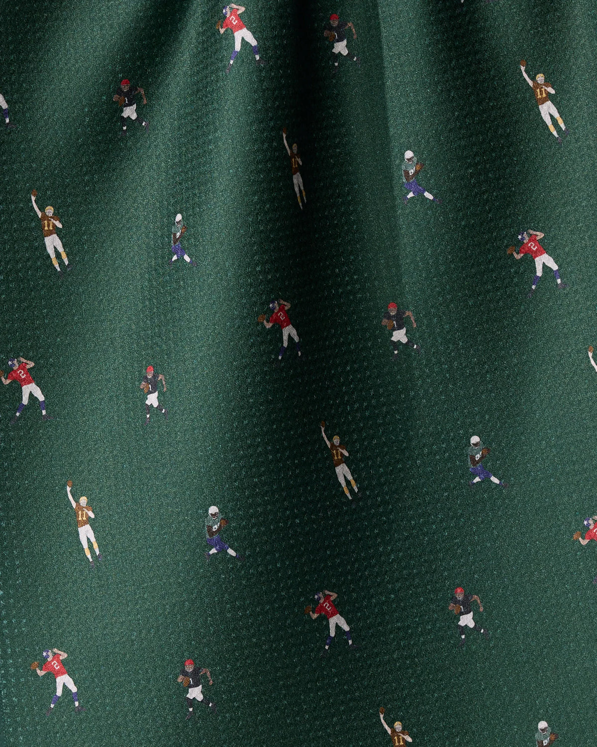 Geometry Roster tea towel in dark green, quick-drying fabric with a repeating print of small football players in various uniforms running and throwing balls.