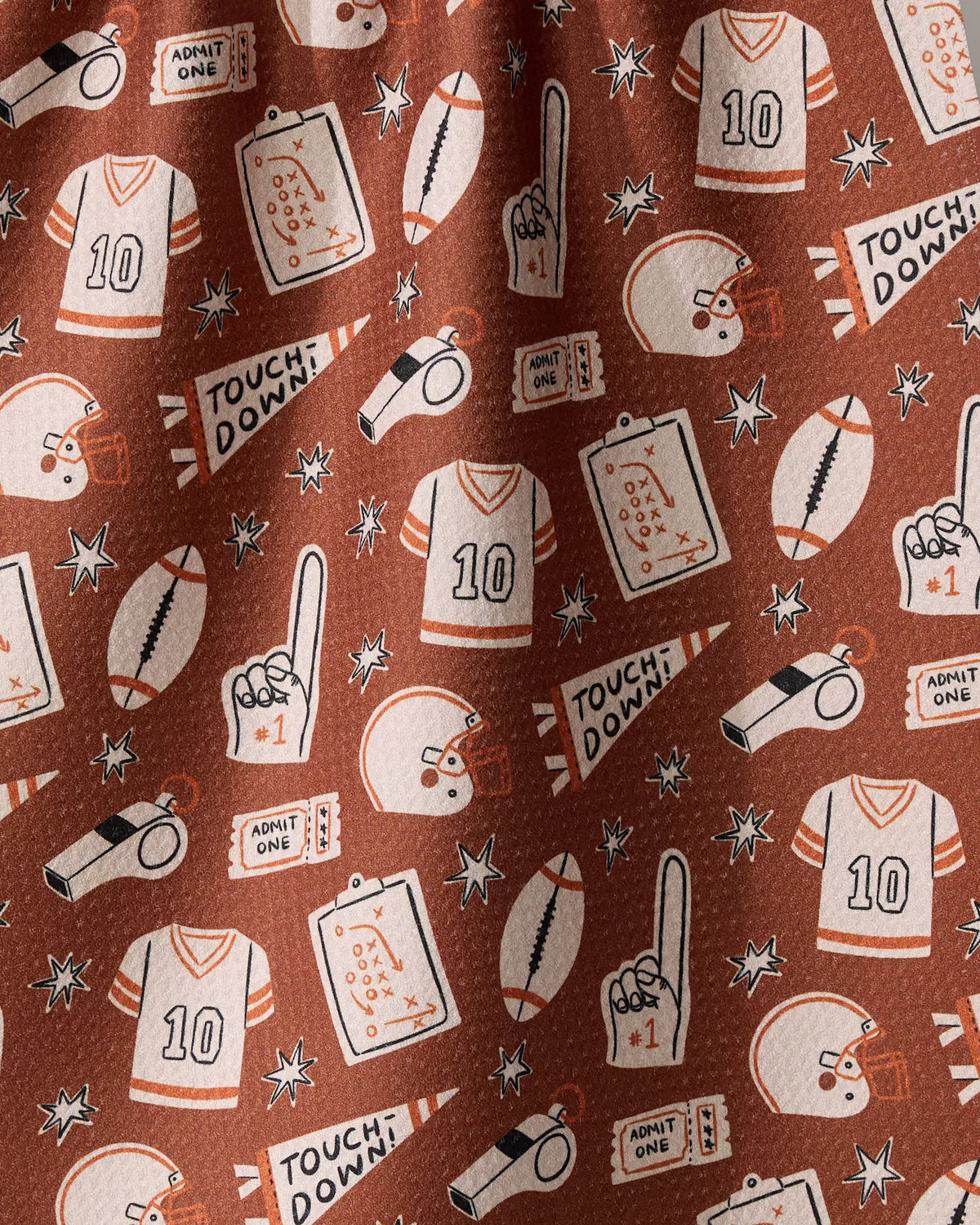 Team Huddle recycled kitchen towel featuring football-themed illustrations of jerseys, helmets, footballs, playbooks, whistles, foam fingers, and Admit One tickets.