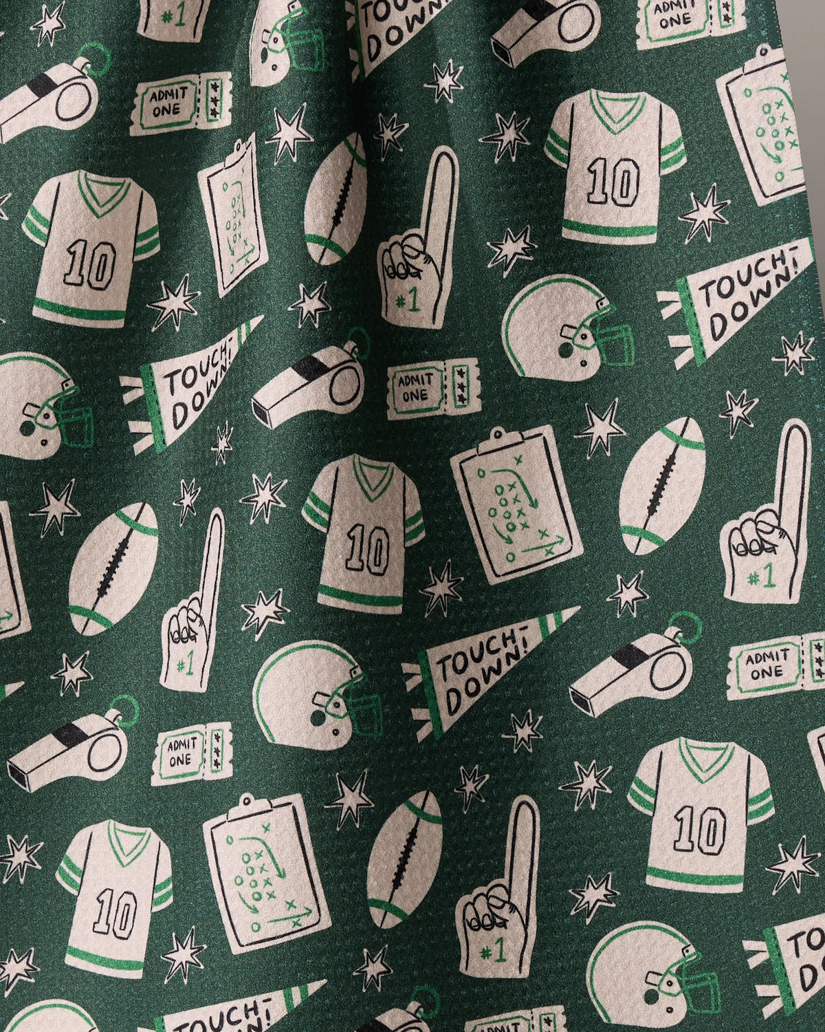 Geometry Team Huddle kitchen towel in dark green with a repeating pattern of white and green football-themed illustrations including jerseys, helmets, whistles, footballs, TOUCHDOWN pennants, and foam fingers.